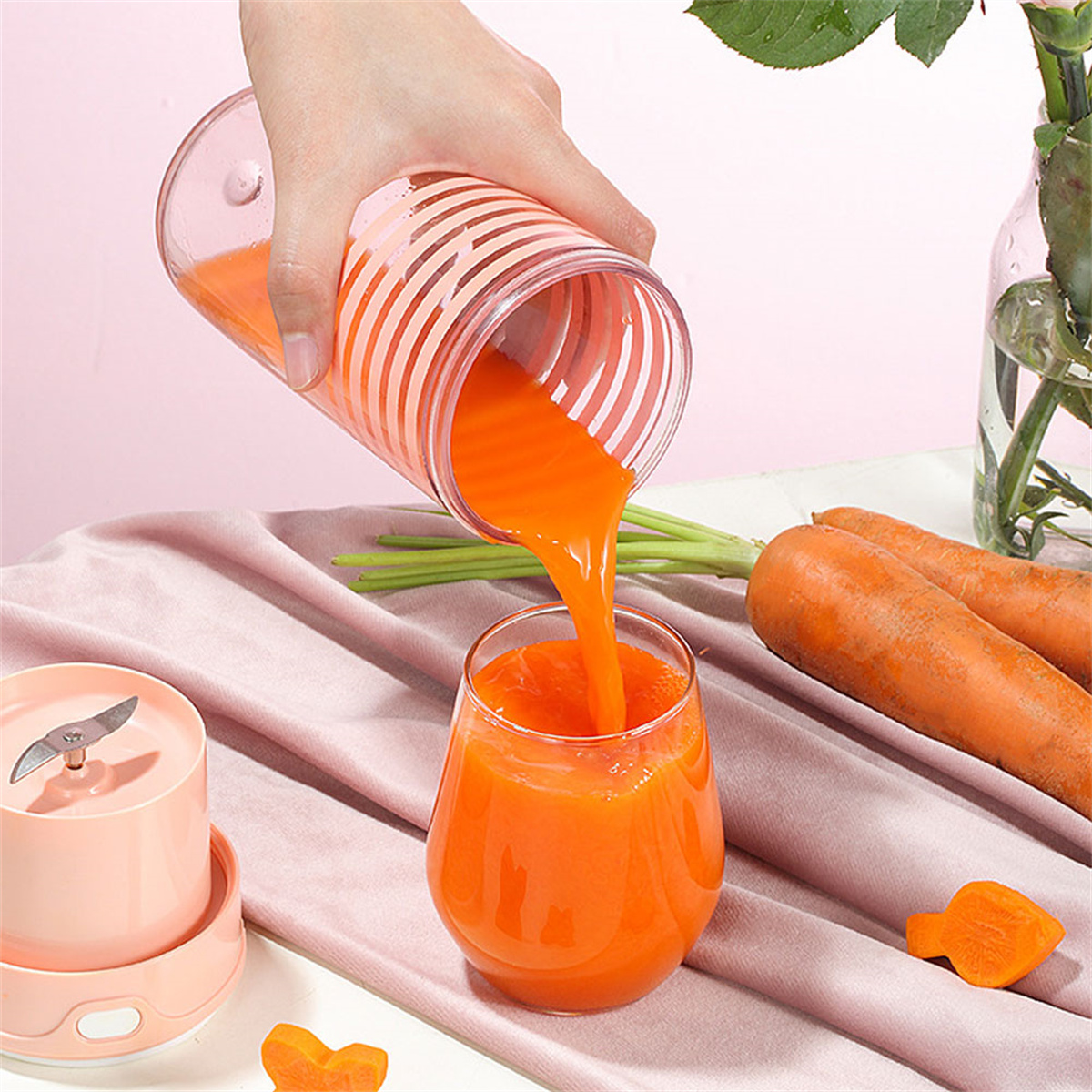 Eine Person gießt Orangensaft in ein Glas, Karotten im Hintergrund.