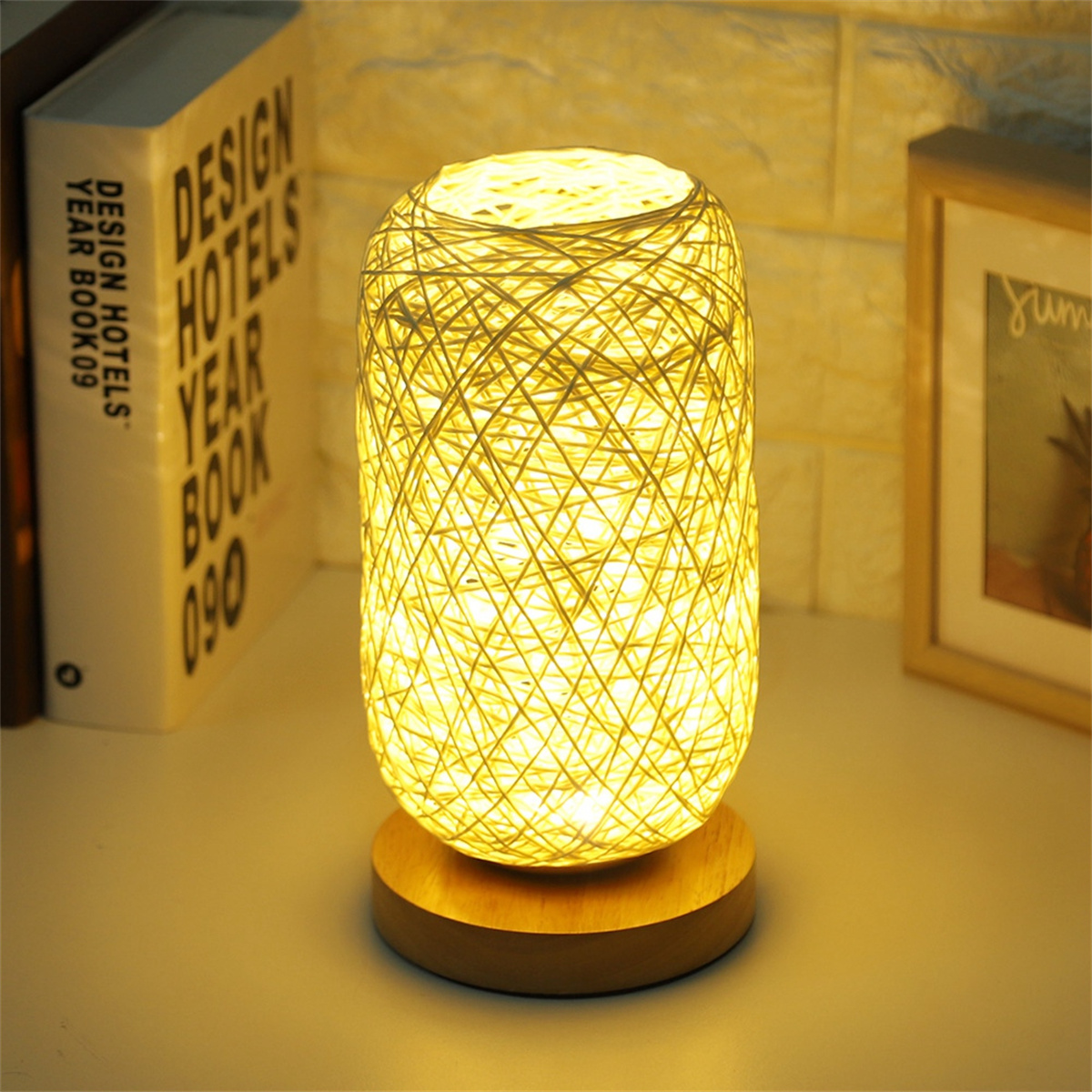Gelbe Lampe mit Holzsockel, Bücher an der Seite. Weiße Oberfläche.