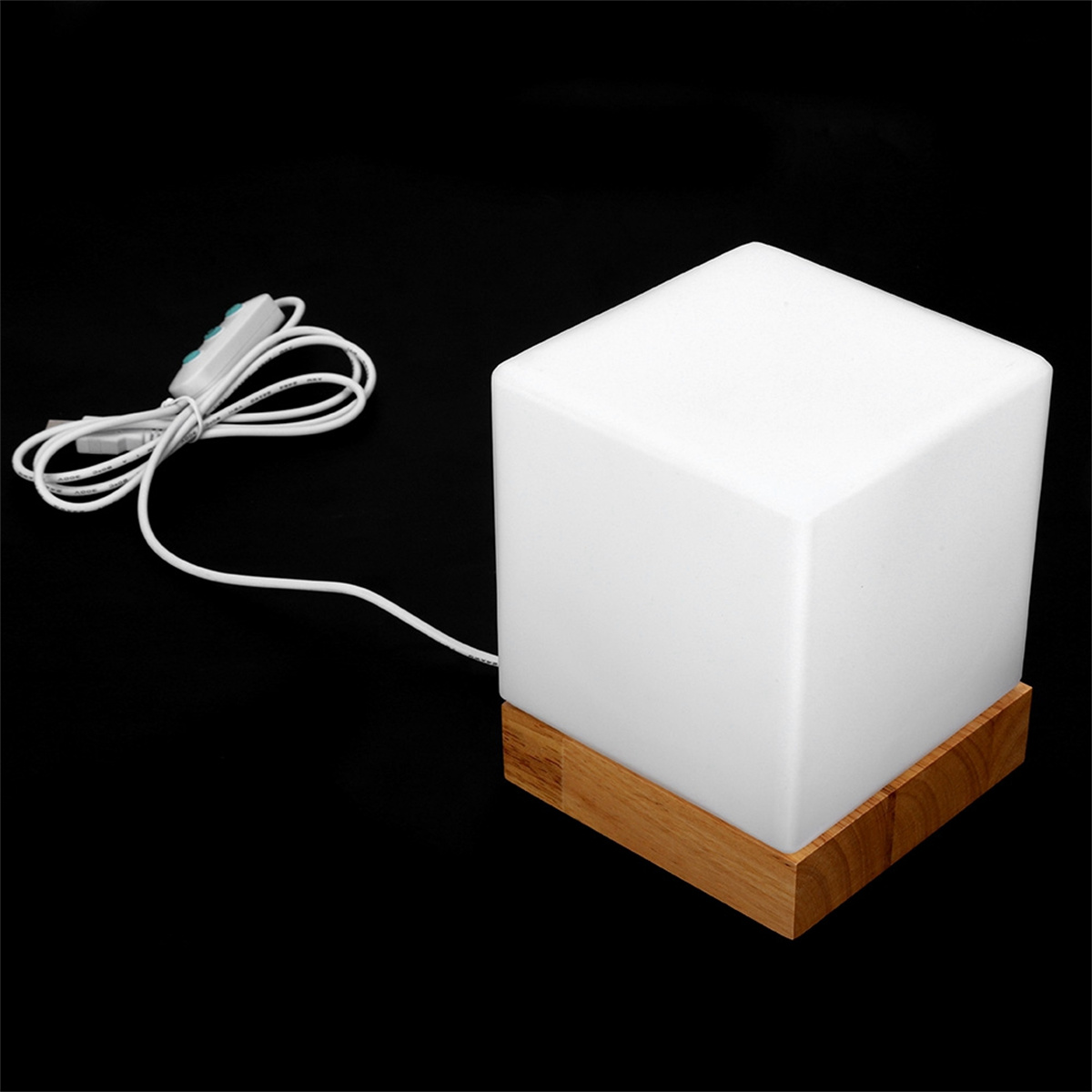 Weißer würfelförmiger Lampe mit Holzsockel. Ein weißes Kabel und ein Schalter sind angebracht.
