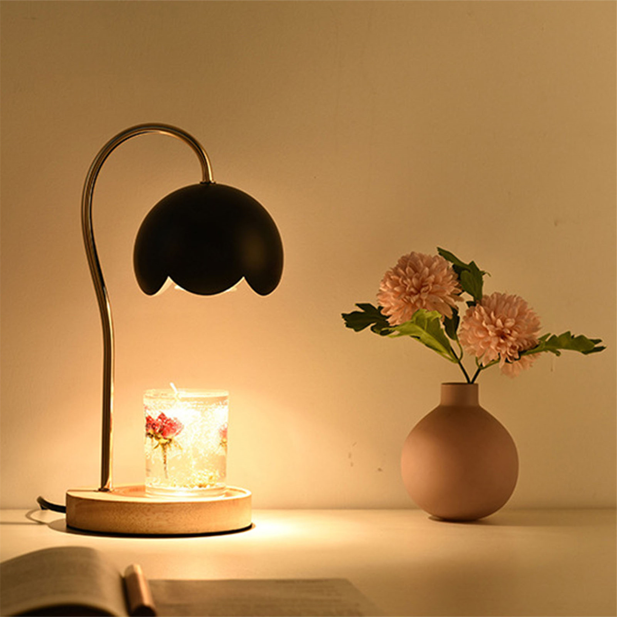 Eine Lampe mit einer Kerze in einem Glas, Blumen in einer Vase und ein Buch.