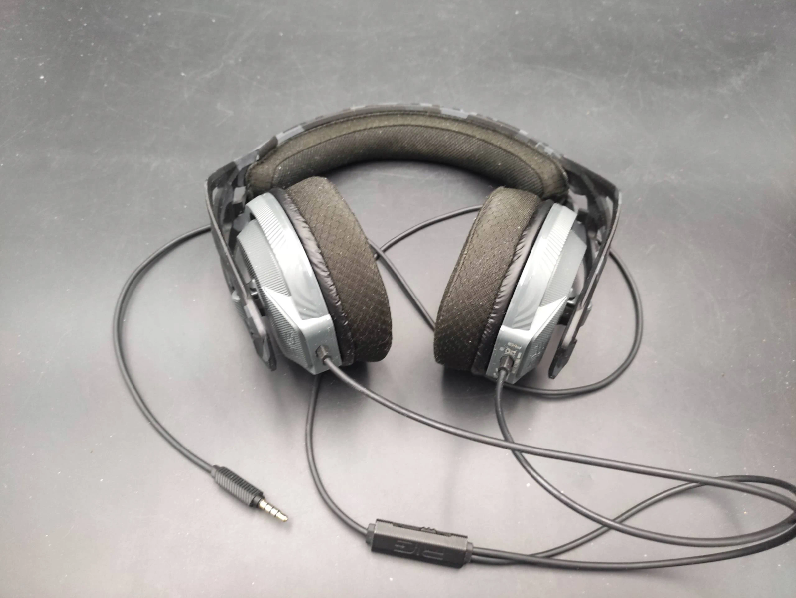 Czarne i szare słuchawki dla graczy na czarnej powierzchni. Mają gniazdo mikrofonu.