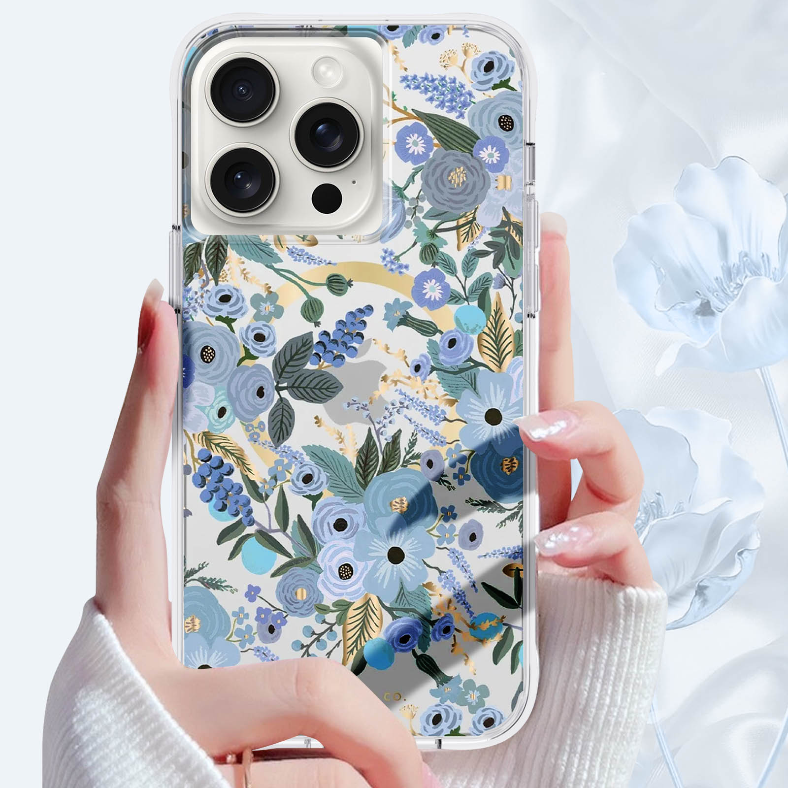 Eine Hand hält ein Telefon mit floraler Hülle. Der Hintergrund ist mit Blumen verschwommen.