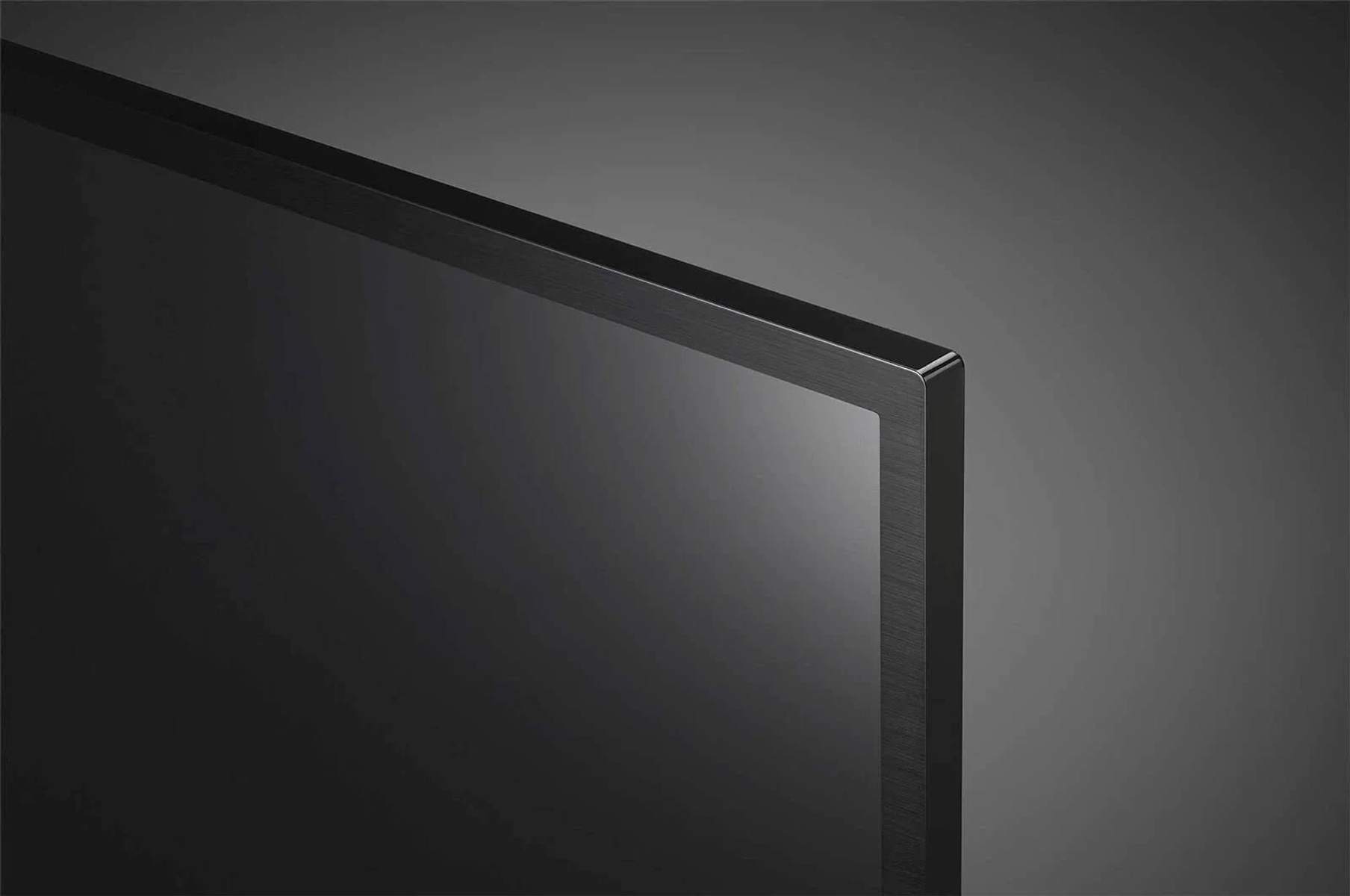 Zbliżenie czarnego ekranu i ramki telewizora. Ekran jest wyłączony, tło jest szare.