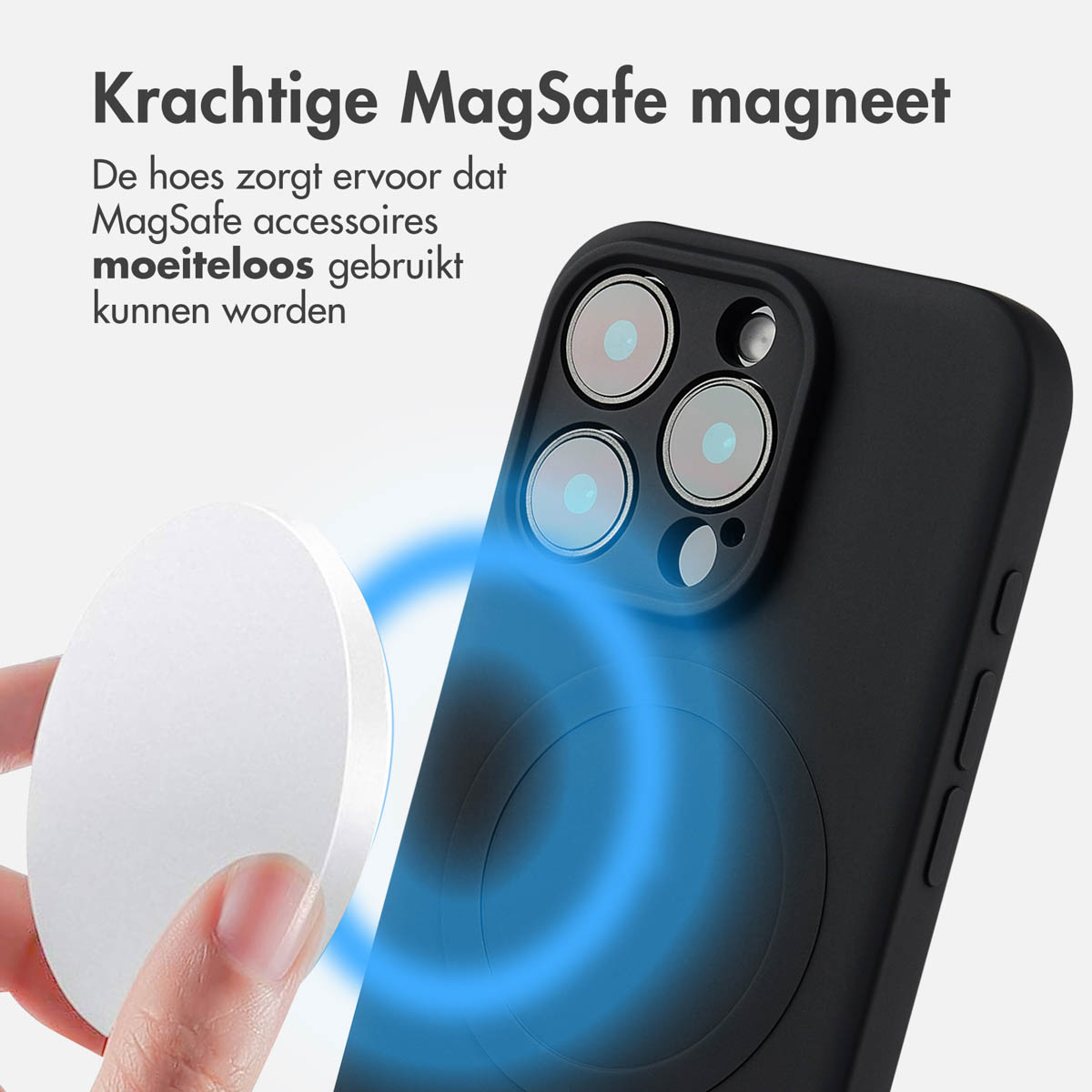 Hand die een witte oplaadpad vasthoudt in de buurt van een zwarte telefoon met een MagSafe-cirkel en tekst.