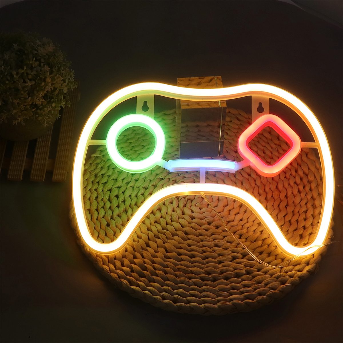 Neon-Gaming-Controller-Licht. Gelber Umriss mit grünen, blauen und roten Innenlichtern. Auf einer Flechtmatte platziert.