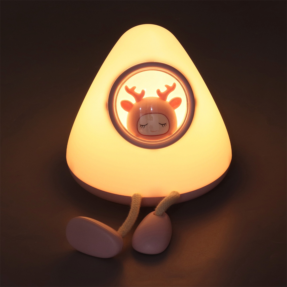Eine Lampe mit einem Hirsch darin, ein beleuchtetes Design. Die Lampe steht auf dunklem Untergrund.