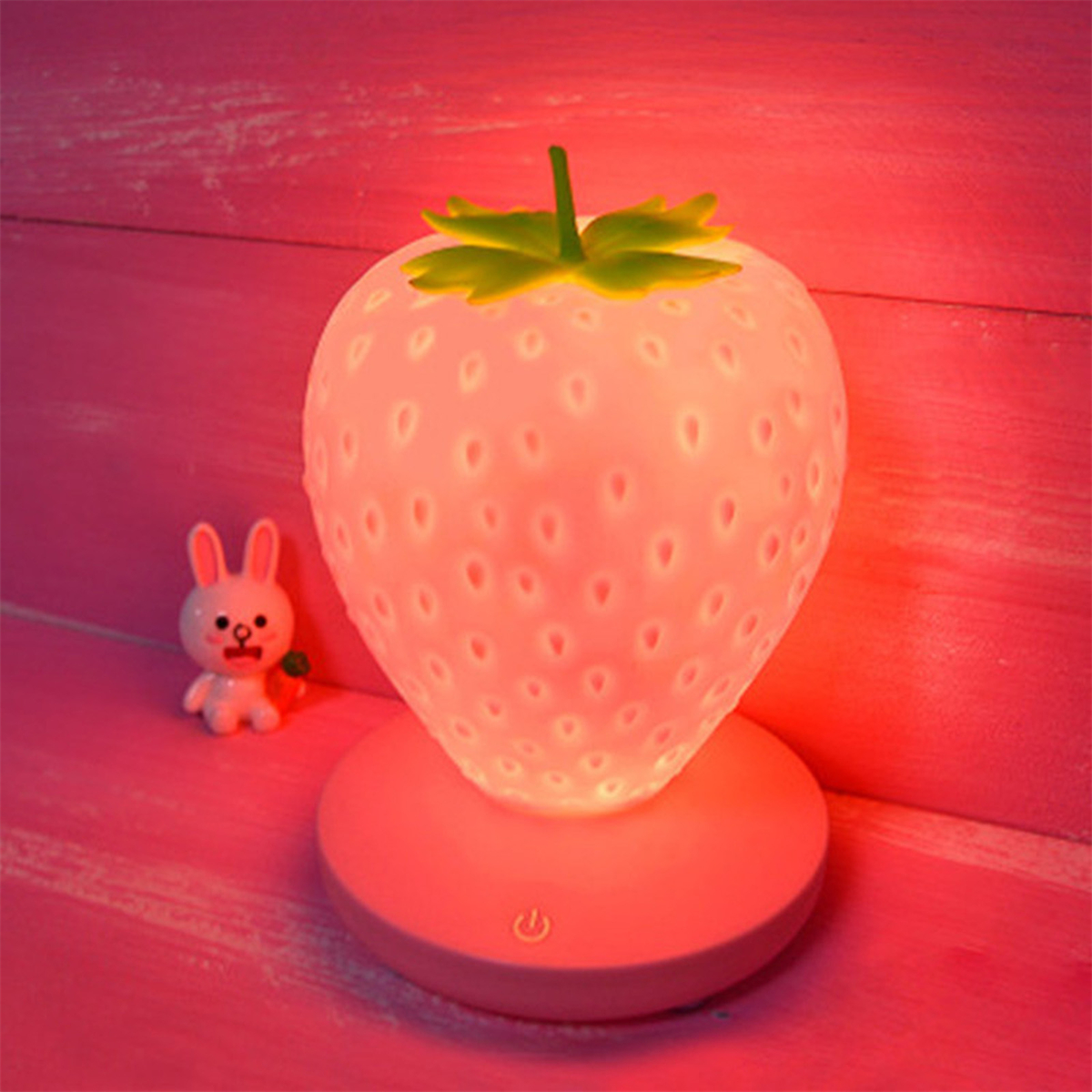 Erdbeerförmige Lampe, pink leuchtend, mit kleiner Hasenfigur daneben.