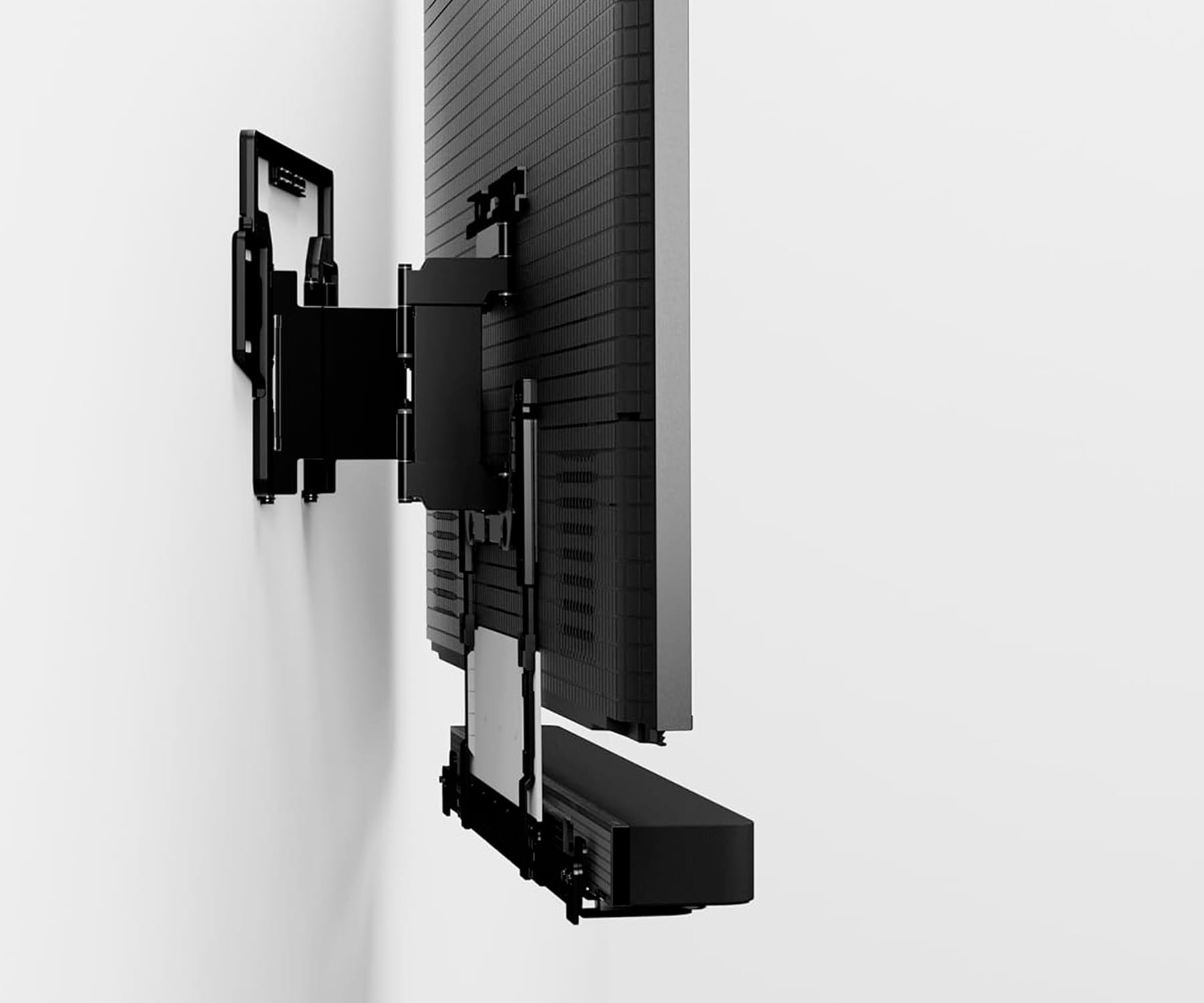 TV negro y barra de sonido en pared blanca con soporte de montaje negro.