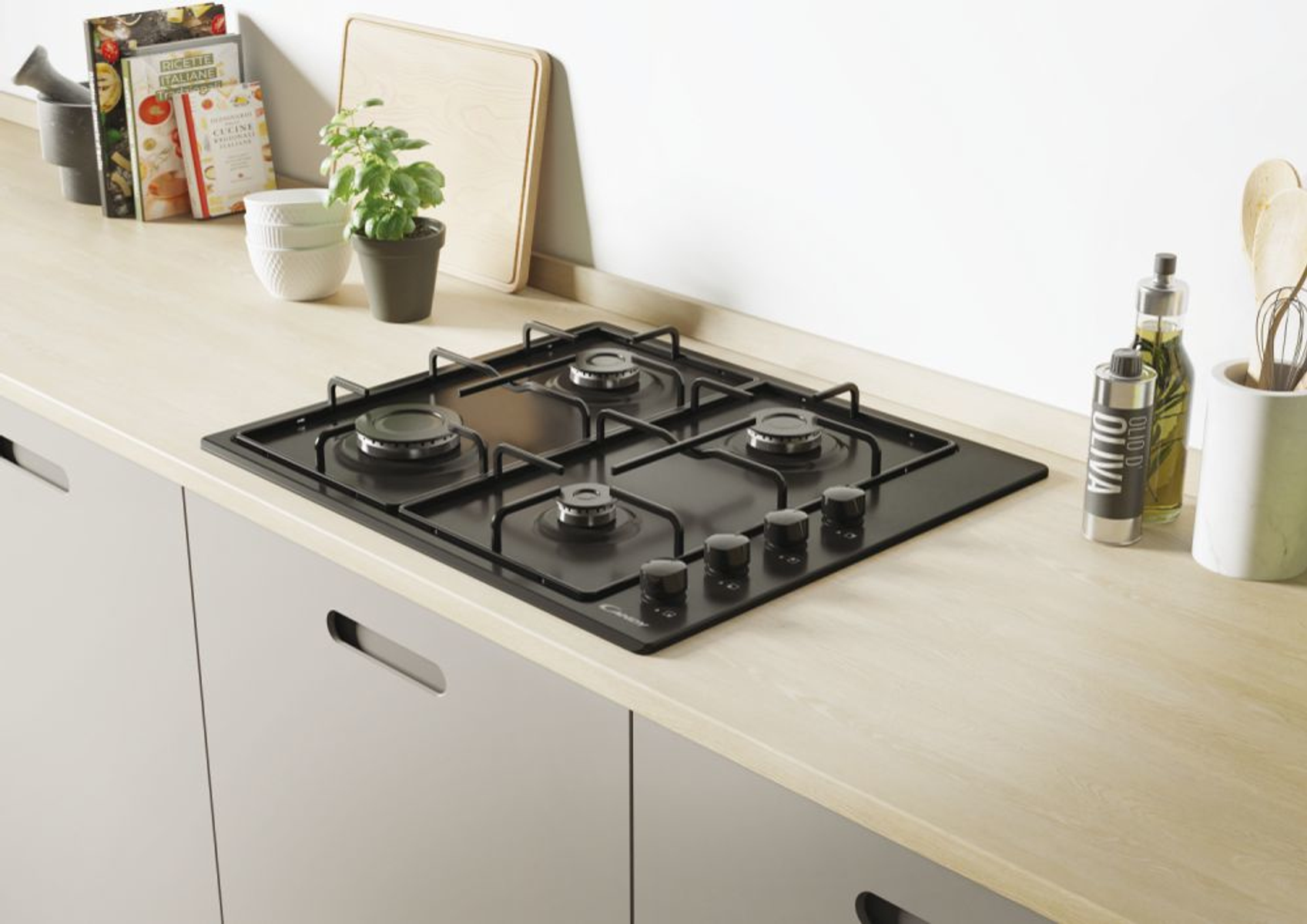 Czarna płyta kuchenna z czterema palnikami i pokrętłami. Blat kuchenny ze sprzętem i książkami.