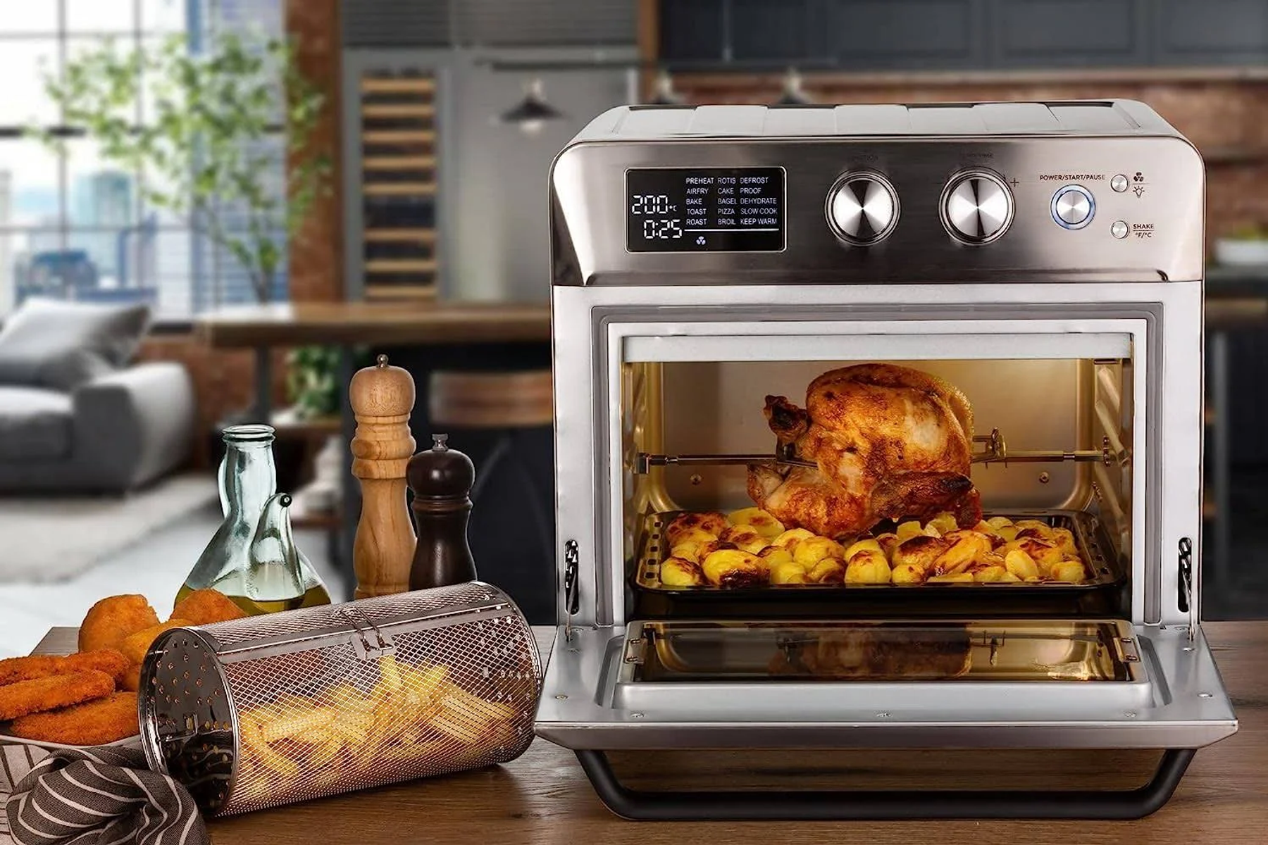 Freidora de aire abierta con comida dentro, incluyendo pollo asado y patatas. Fondo de cocina.