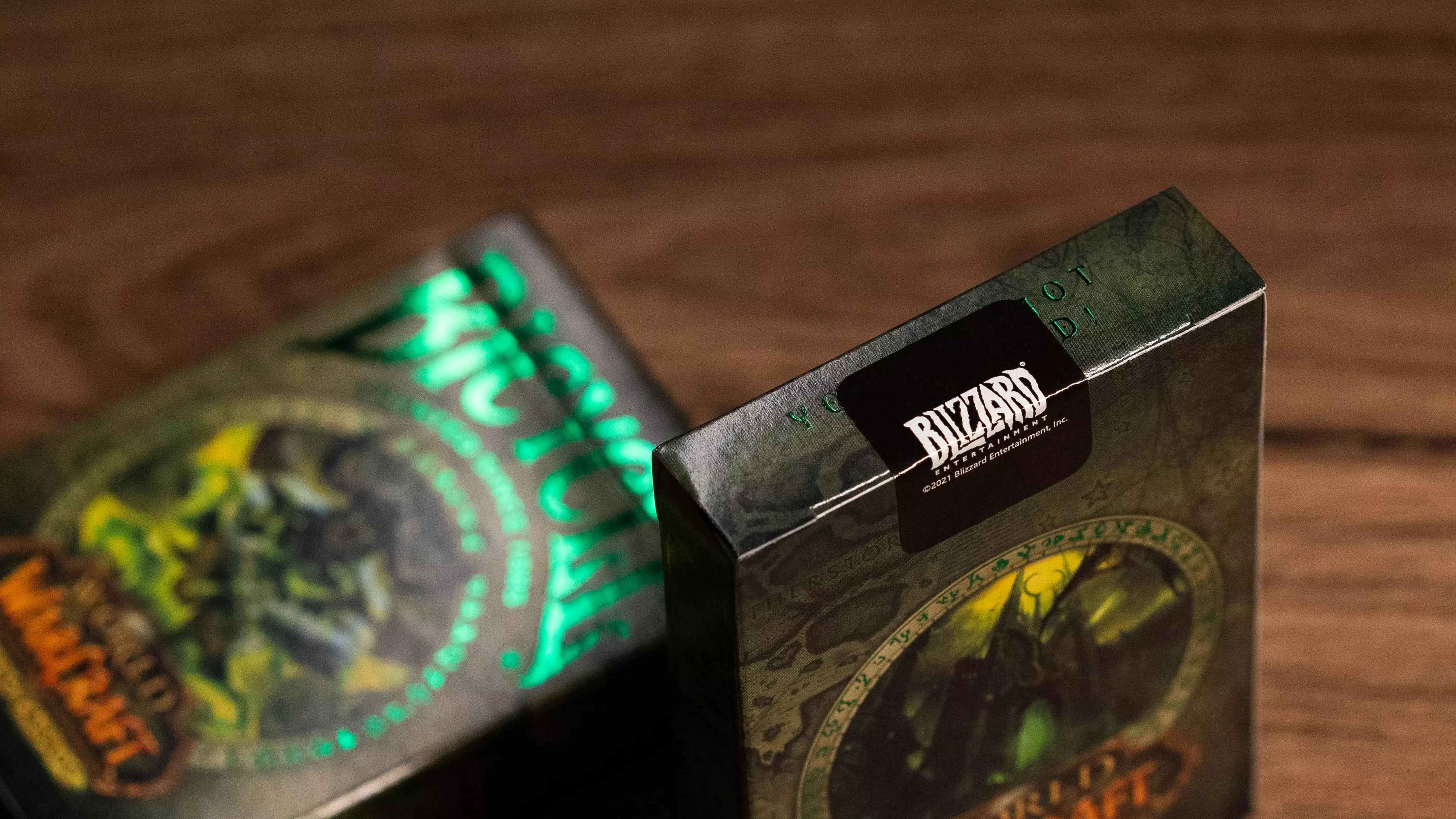Zwei World of Warcraft-Kartenboxen liegen auf einer Holzoberfläche. Blizzard-Logo auf der Box.