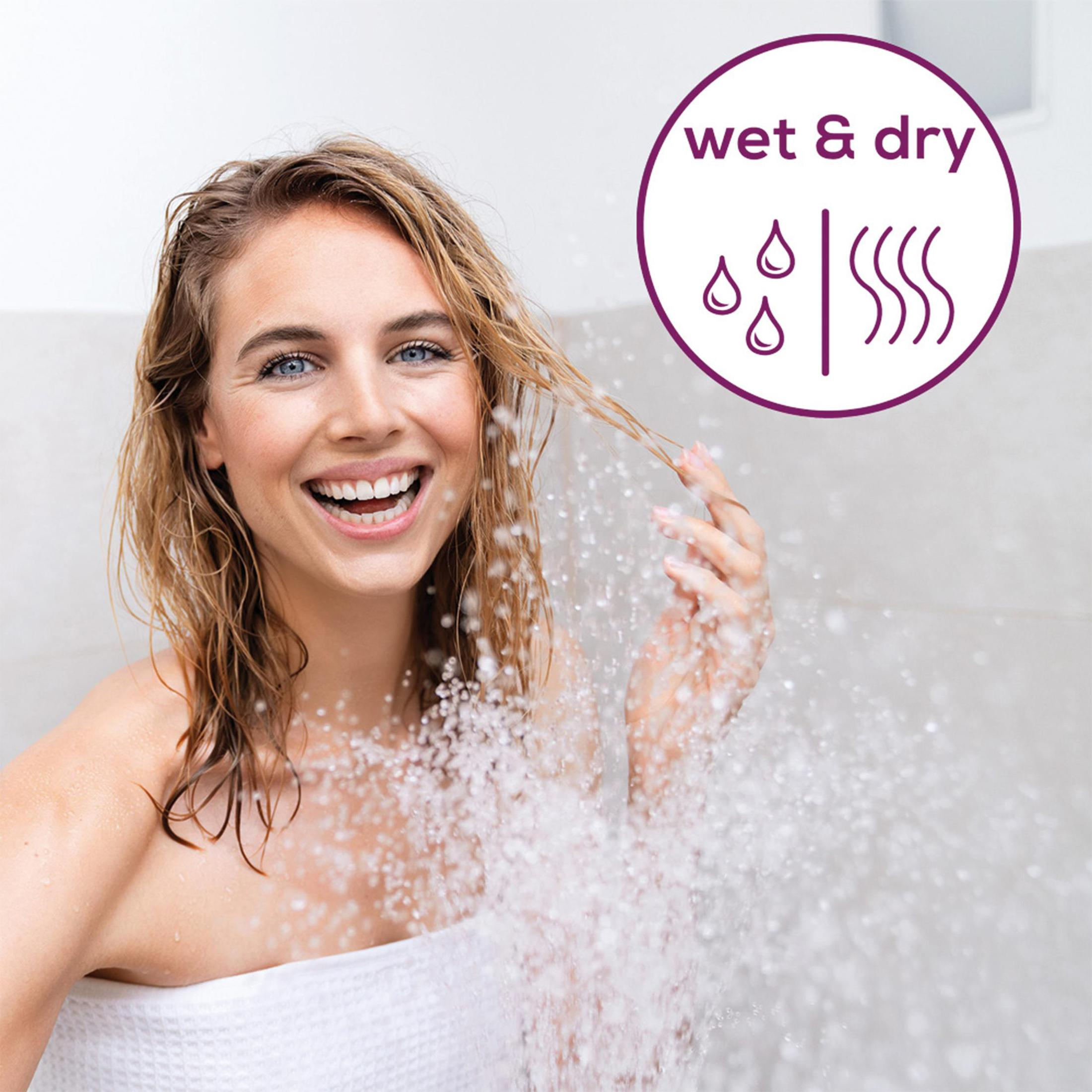 Mujer duchándose. Sonríe y el agua salpica. Texto arriba: 'wet & dry'.