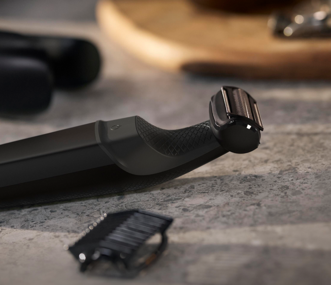 Black electric shaver with blade and extra blade on a gray surface.