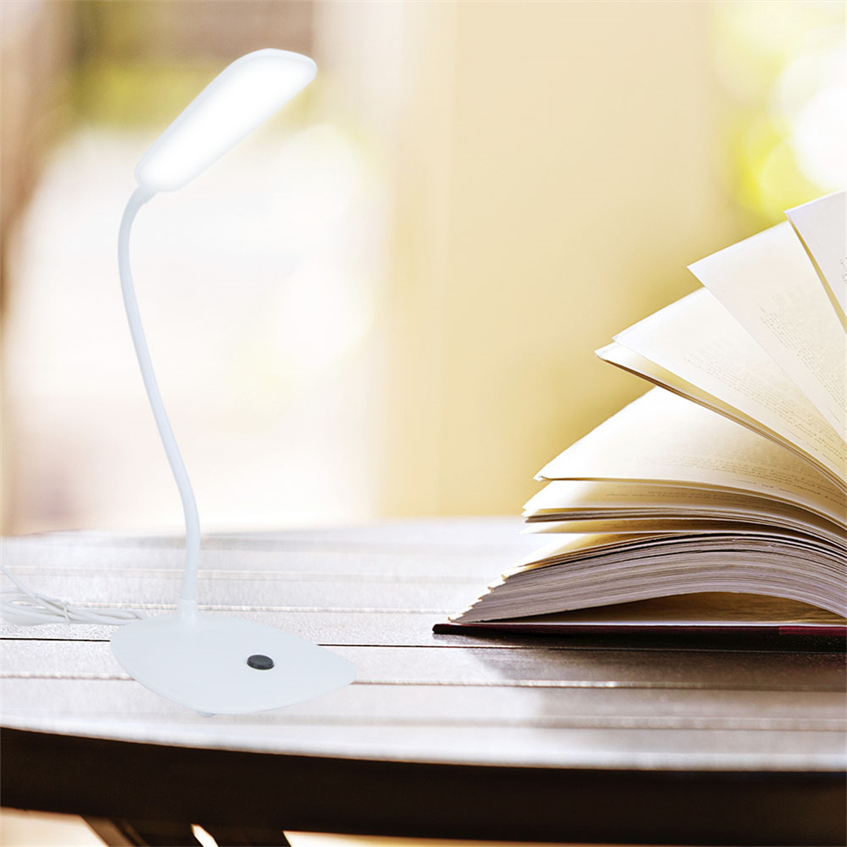 Weiße Schreibtischlampe mit Schwanenhals und gebogenem Hals. Die Lampe befindet sich über einem offenen Buch.