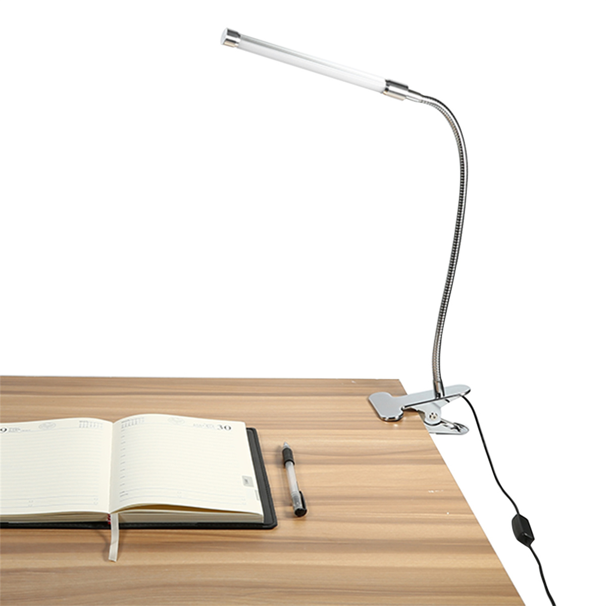 Verstellbare Schreibtischlampe mit flexiblem Hals, Notizbuch und Stift auf dem Schreibtisch.