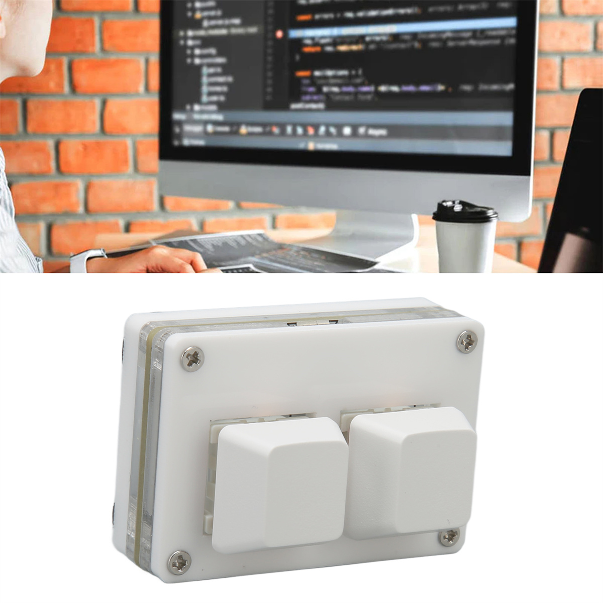 Eine Person, die einen Computer benutzt. Ein Gerät mit zwei großen weißen Knöpfen steht auf dem Tisch.