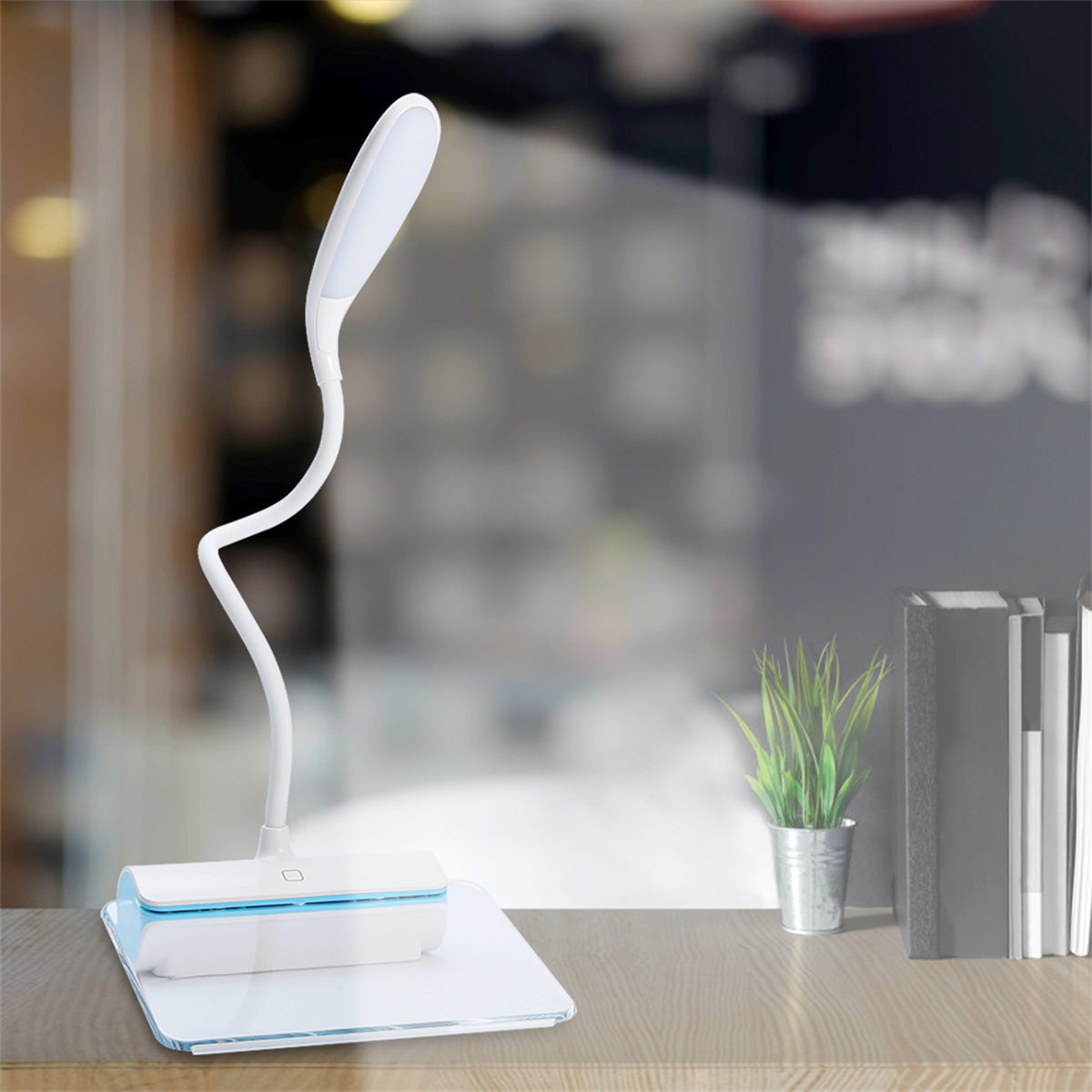 Weiße Schreibtischlampe mit gebogenem Hals. Die Lampe steht auf einem weißen Sockel.