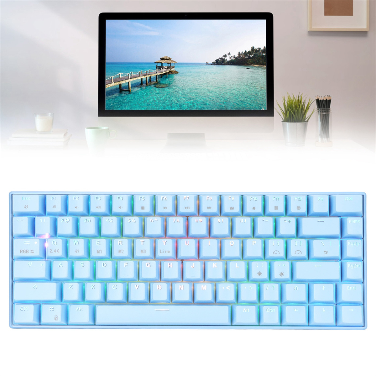 Blaue Tastatur auf einem Schreibtisch. Ein Monitor zeigt eine Strandszene. Daneben eine Pflanze und Stifte.