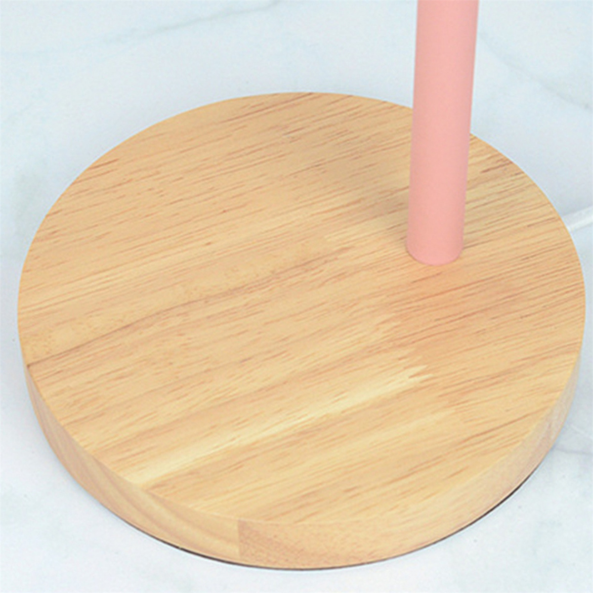 Ein runder Holzsockel mit einem rosa Pfahl, wahrscheinlich ein Lampensockel.
