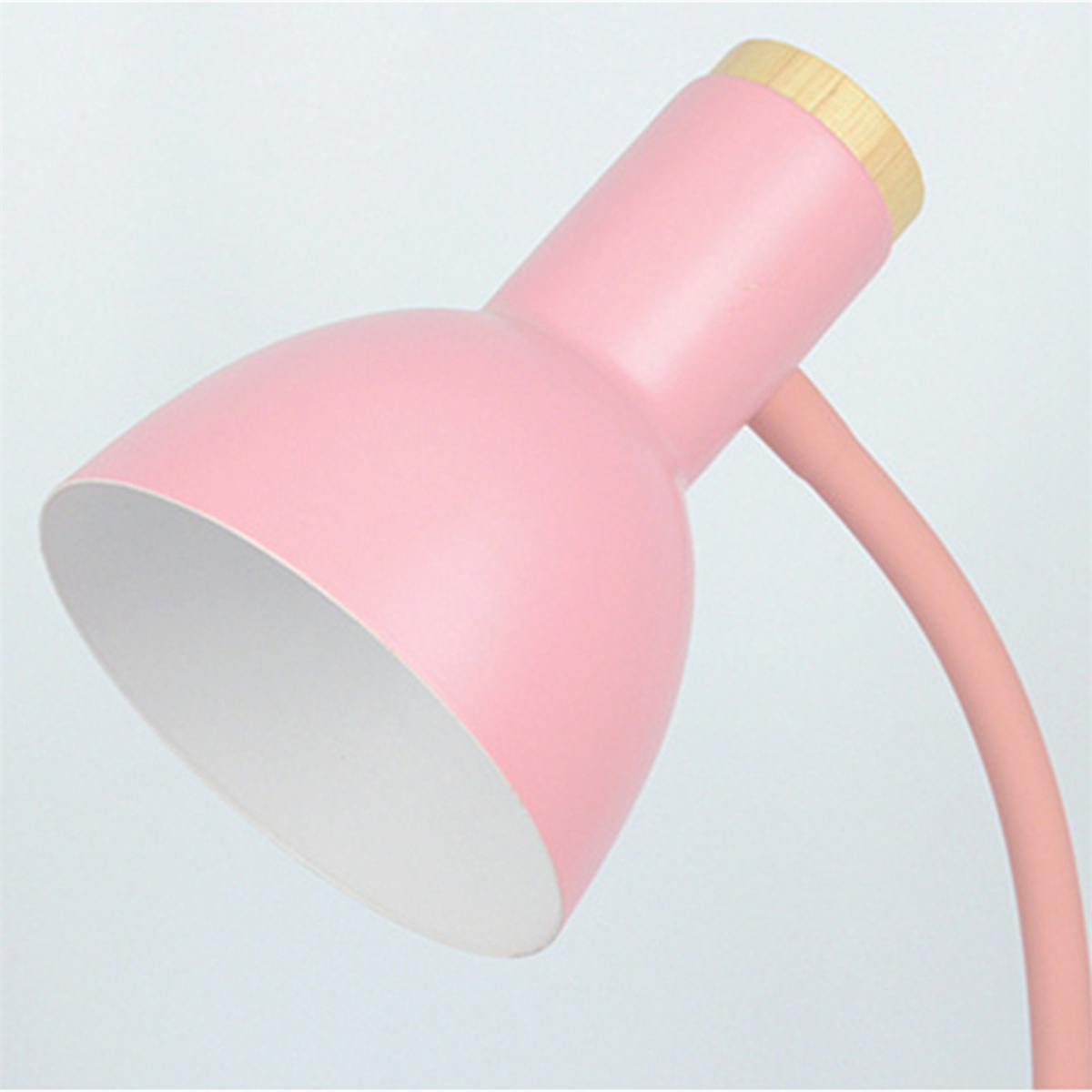 Rosafarbene Schreibtischlampe mit weißem Innenraum, Holzaufsatz und flexiblem Arm. Nach oben abgewinkelt.