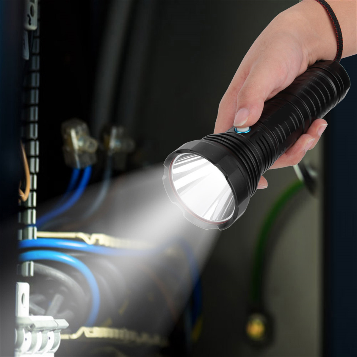 Hand hält schwarze Taschenlampe und beleuchtet elektrische Komponenten in einer dunklen Tafel.