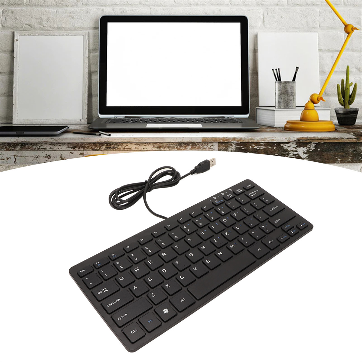 Schwarze Tastatur mit USB-Kabel. Im Hintergrund ein Laptop. Die Tastatur steht auf einem weißen Tisch.