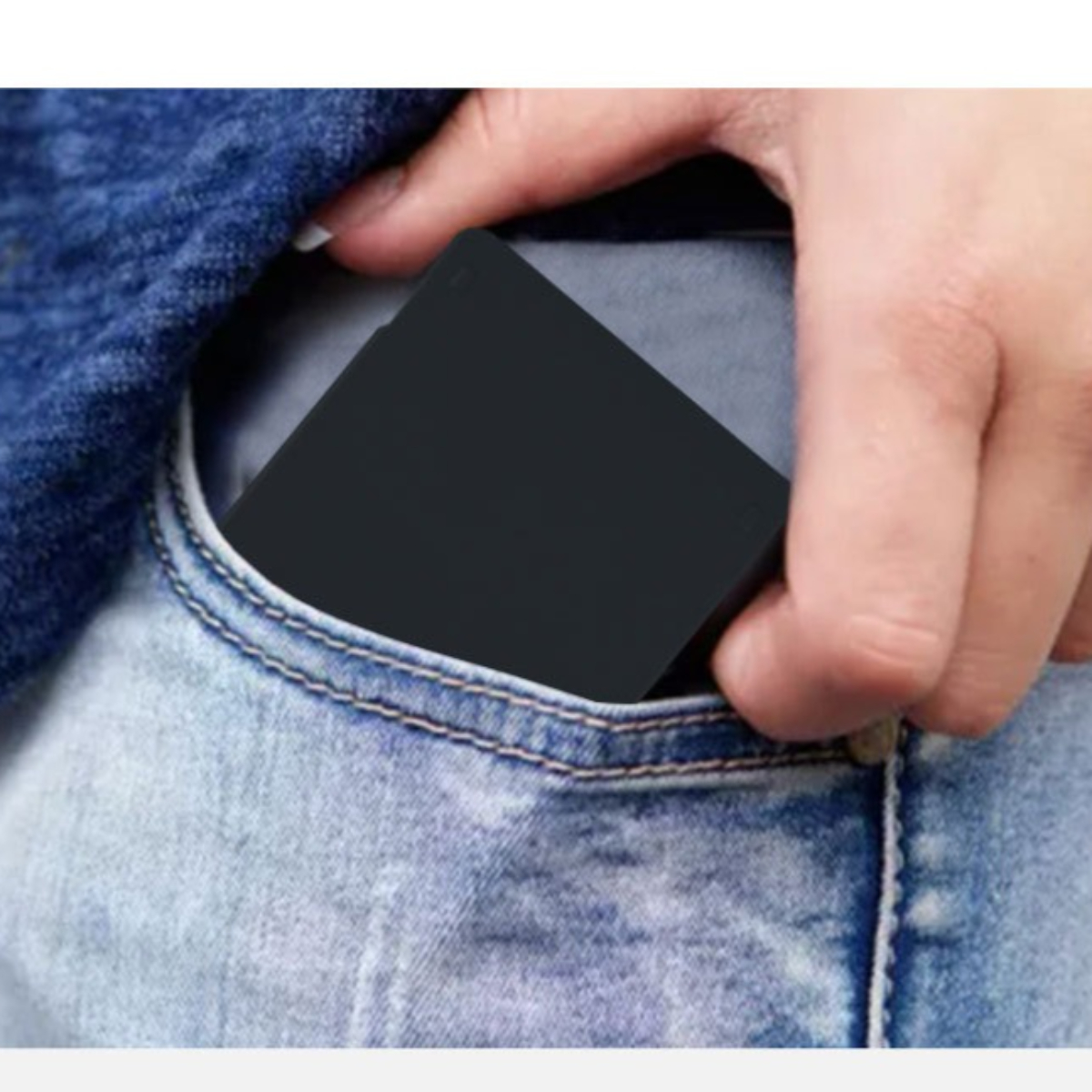 Schwarzes Objekt in einer Jeanstasche, sichtbare Hand.