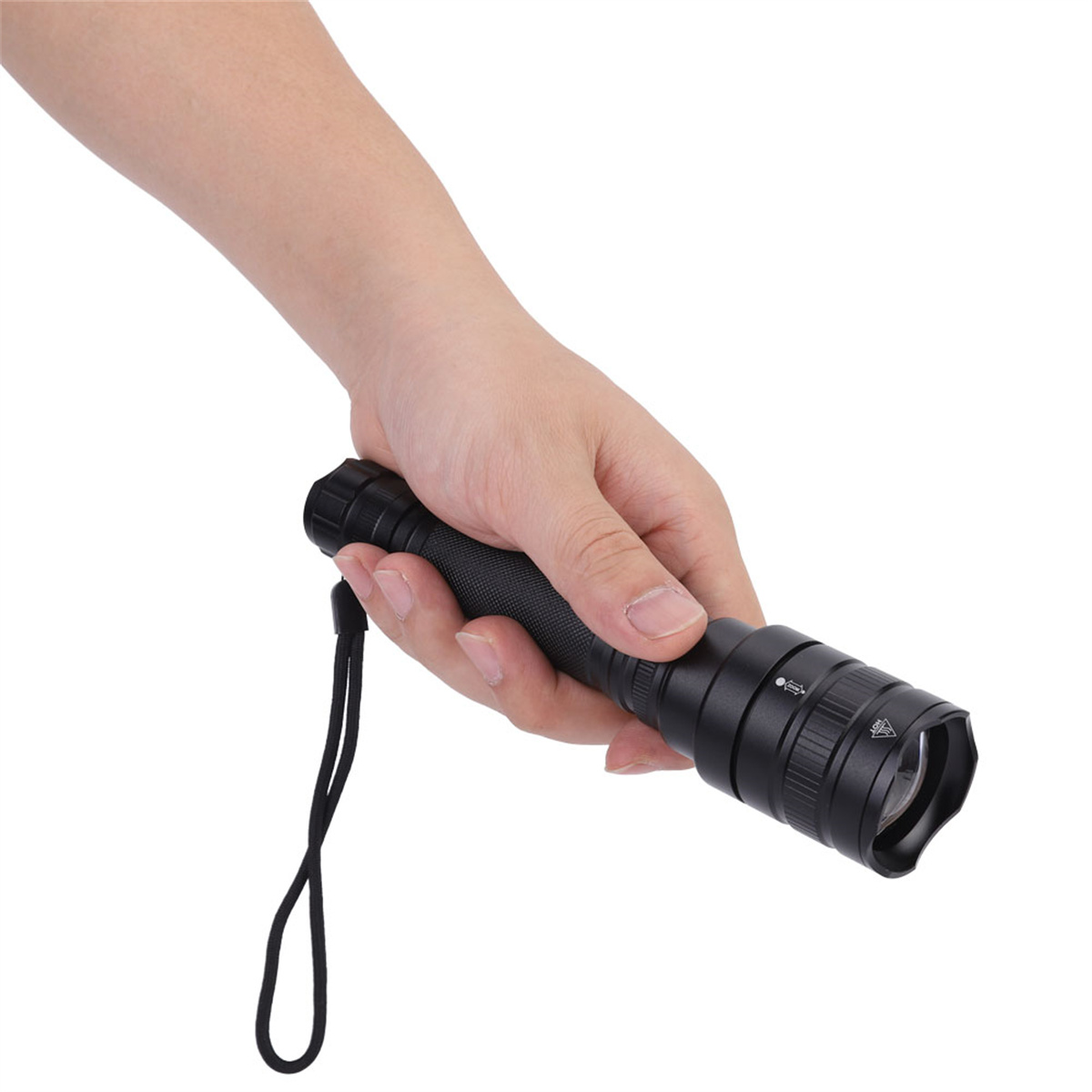 Hand hält eine schwarze Taschenlampe mit Handschlaufe. Weißer Hintergrund.