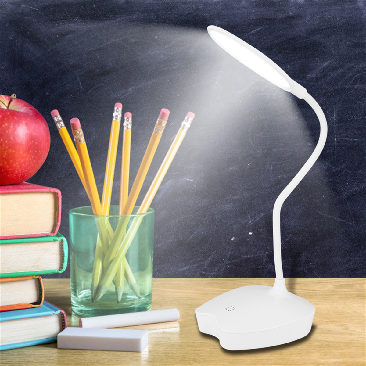 Weiße Schreibtischlampe mit Bleistiften, Apfel und Tafel.