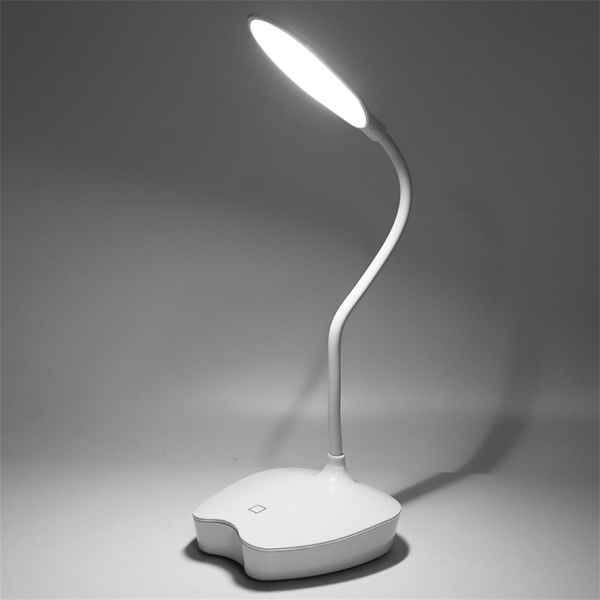Eine weiße Schreibtischlampe mit flexiblem Arm, eingeschaltet, vor grauem Hintergrund.