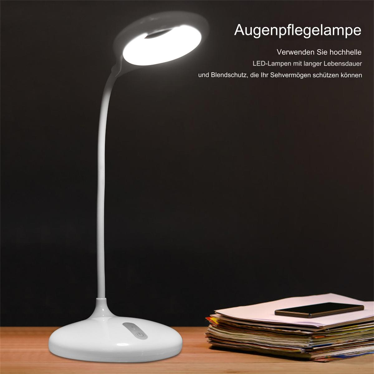 Eine weiße Schreibtischlampe beleuchtet einen Schreibtisch mit einem Stapel Papier und einem Telefon.