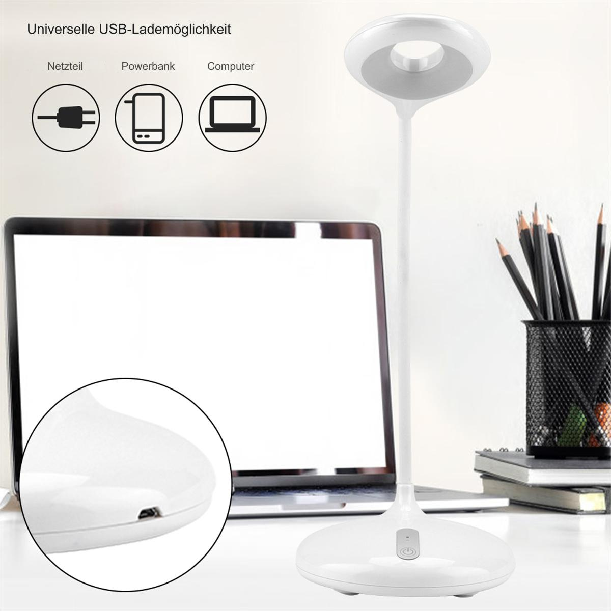Eine weiße Schreibtischlampe mit rundem Leuchtkopf. Ein USB-Ladeanschluss wird gezeigt. Ein Laptop und Bleistifte sind im Hintergrund.