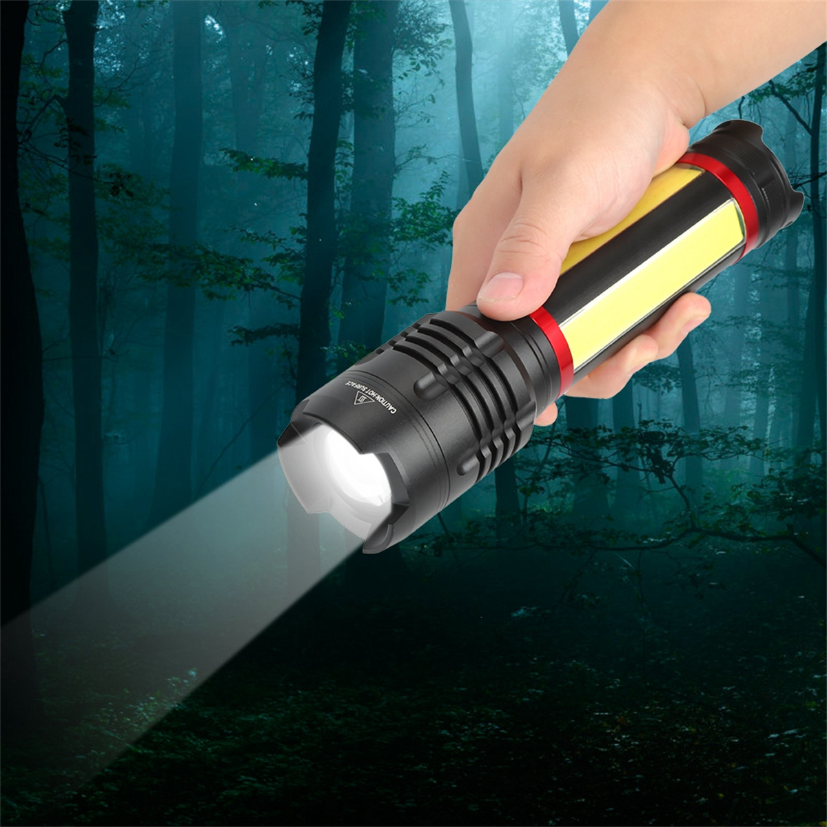 Die Hand einer Person, die eine schwarz-gelbe Taschenlampe mit hellem Strahl in einem dunklen Wald hält.