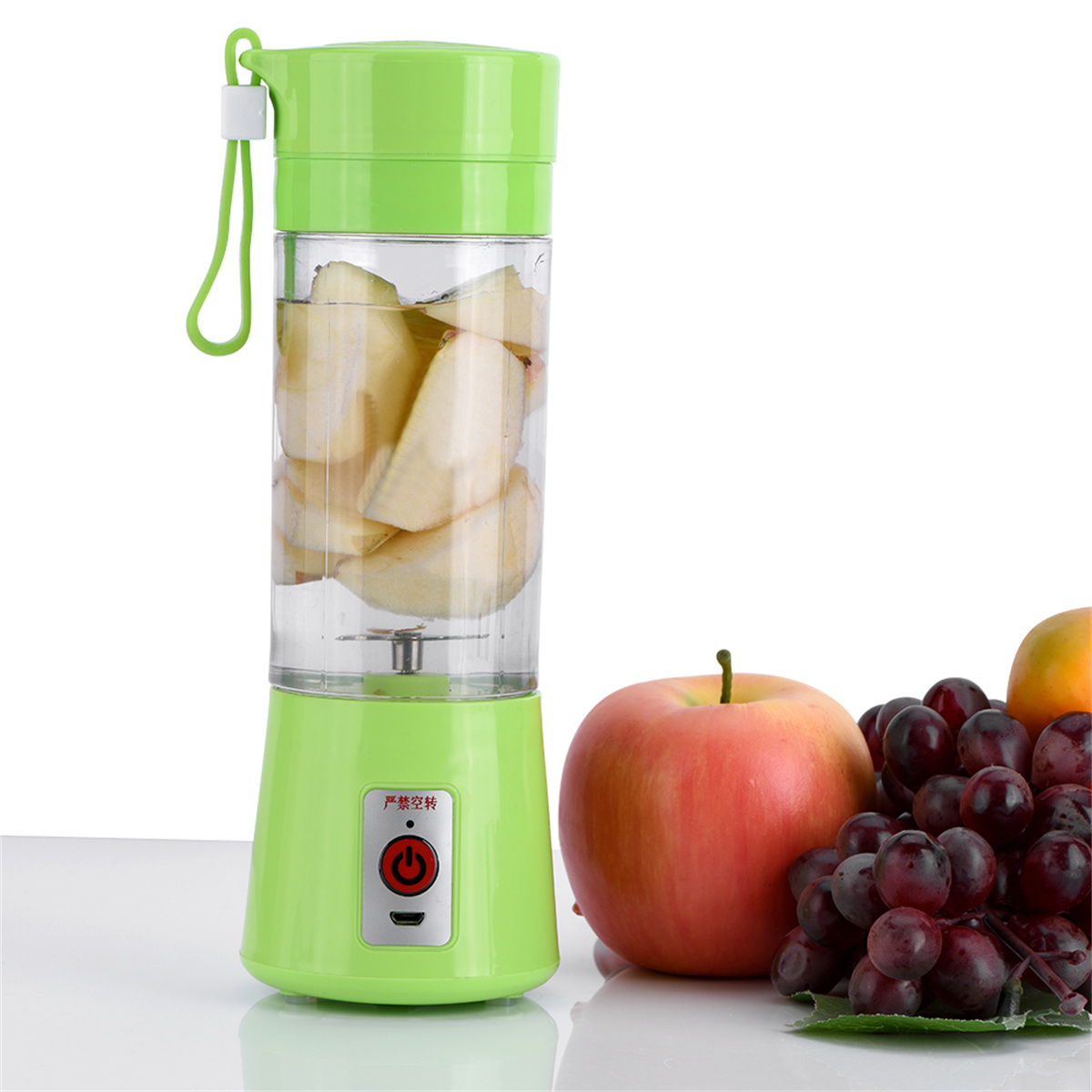Grüner Mixer mit Äpfeln. Apfel und Trauben daneben.