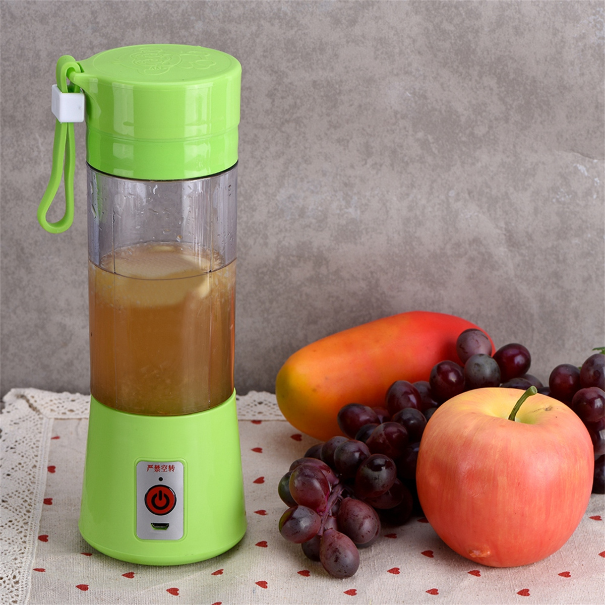 Ein grüner Mixer mit Obst und einem grünen Deckel. Enthält eine Papaya, Trauben und einen Apfel.