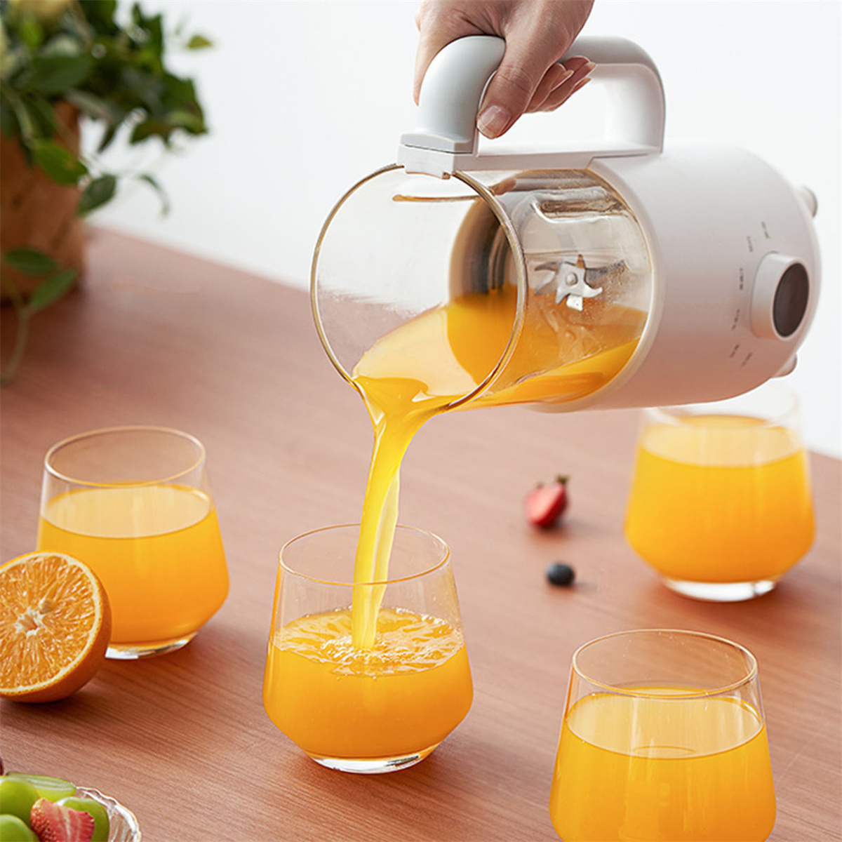 Eine Person gießt Orangensaft in Gläser. Auf dem Tisch liegen Orangen und Früchte.