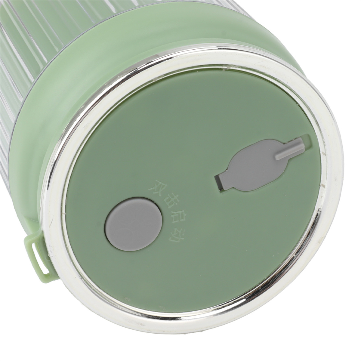 Grüne und transparente Mixbecherbasis. Oben befindet sich eine graue Taste. Der Deckel hat eine kleine Öffnung.