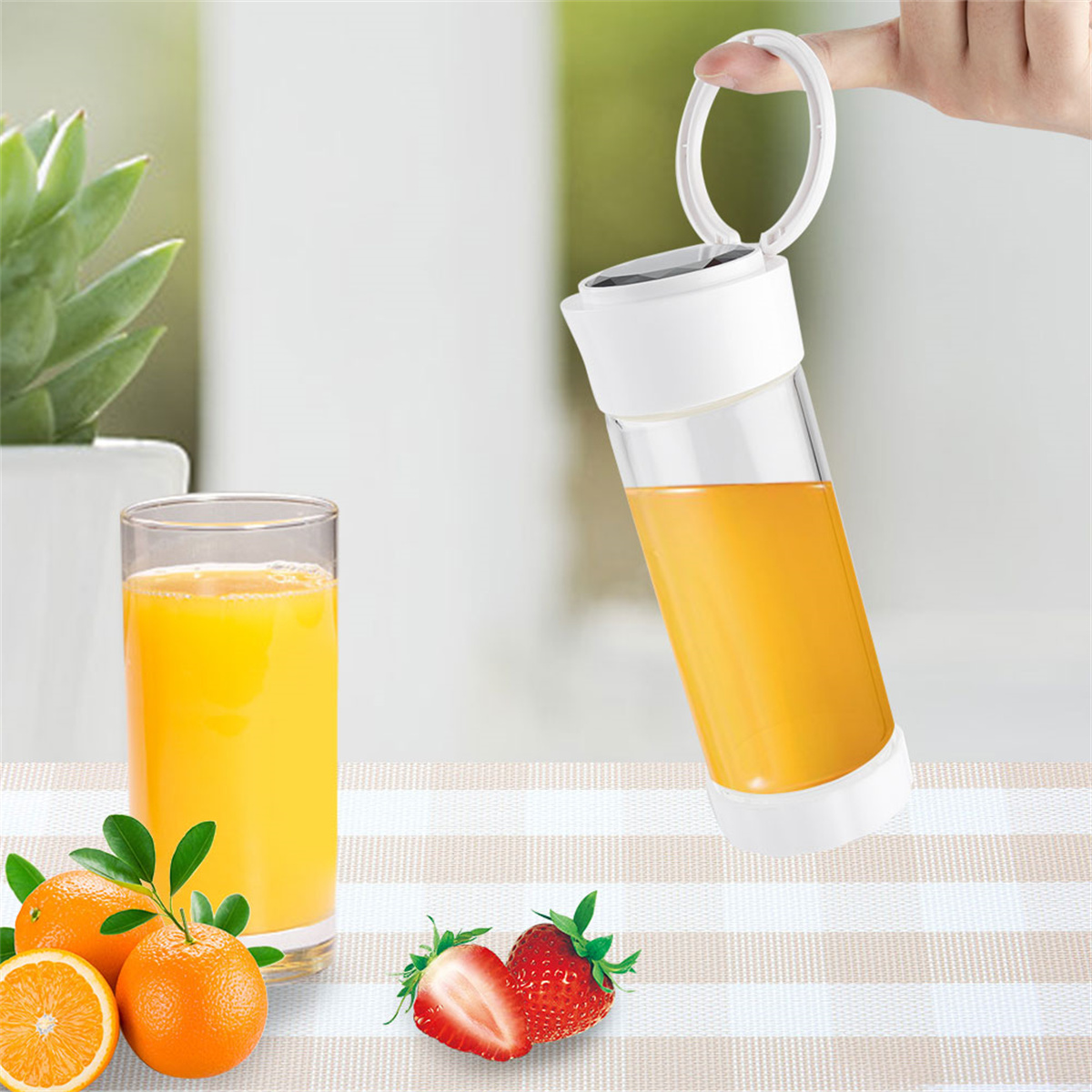 Ein tragbarer Mixer mit Orangensaft, der in ein Glas gegossen wird. Orangen und Erdbeeren sind in der Nähe.