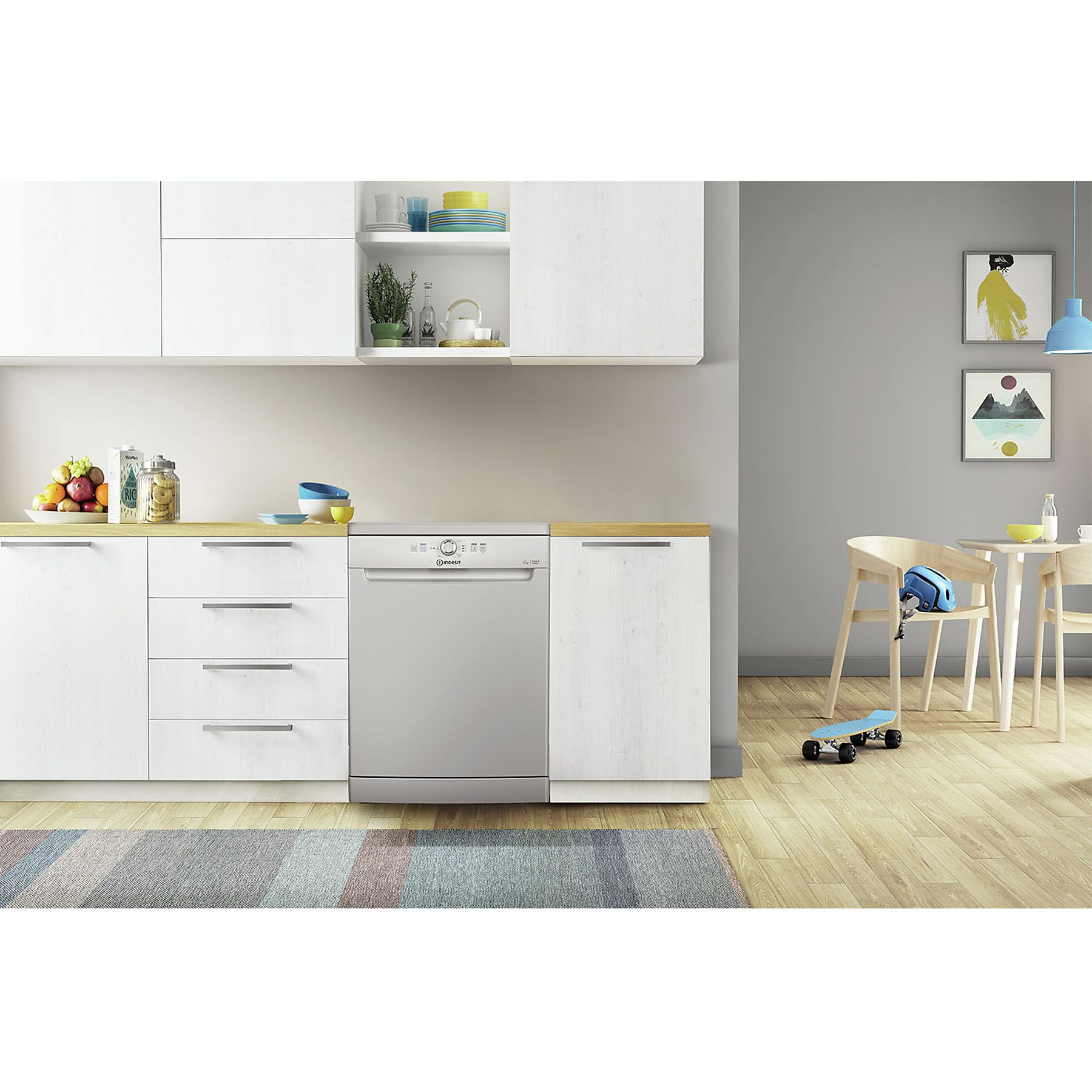 Cucina moderna con mobili bianchi, lavastoviglie in acciaio inox e tappeto colorato. Tavolo e sedia sullo sfondo.