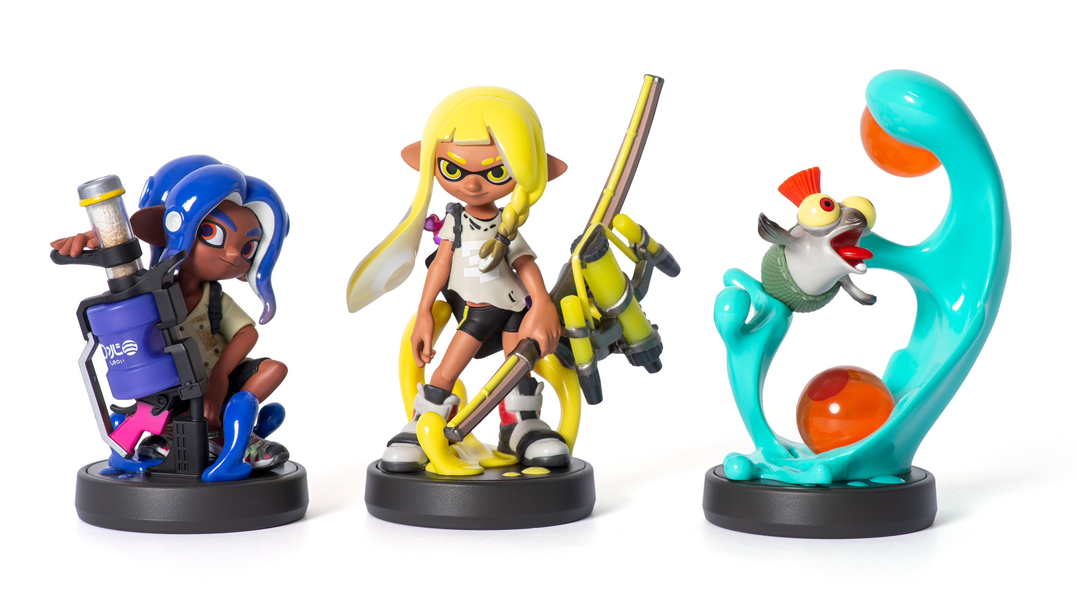 Trzy figurki amiibo Splatoon na białej powierzchni, reprezentujące różne postacie.