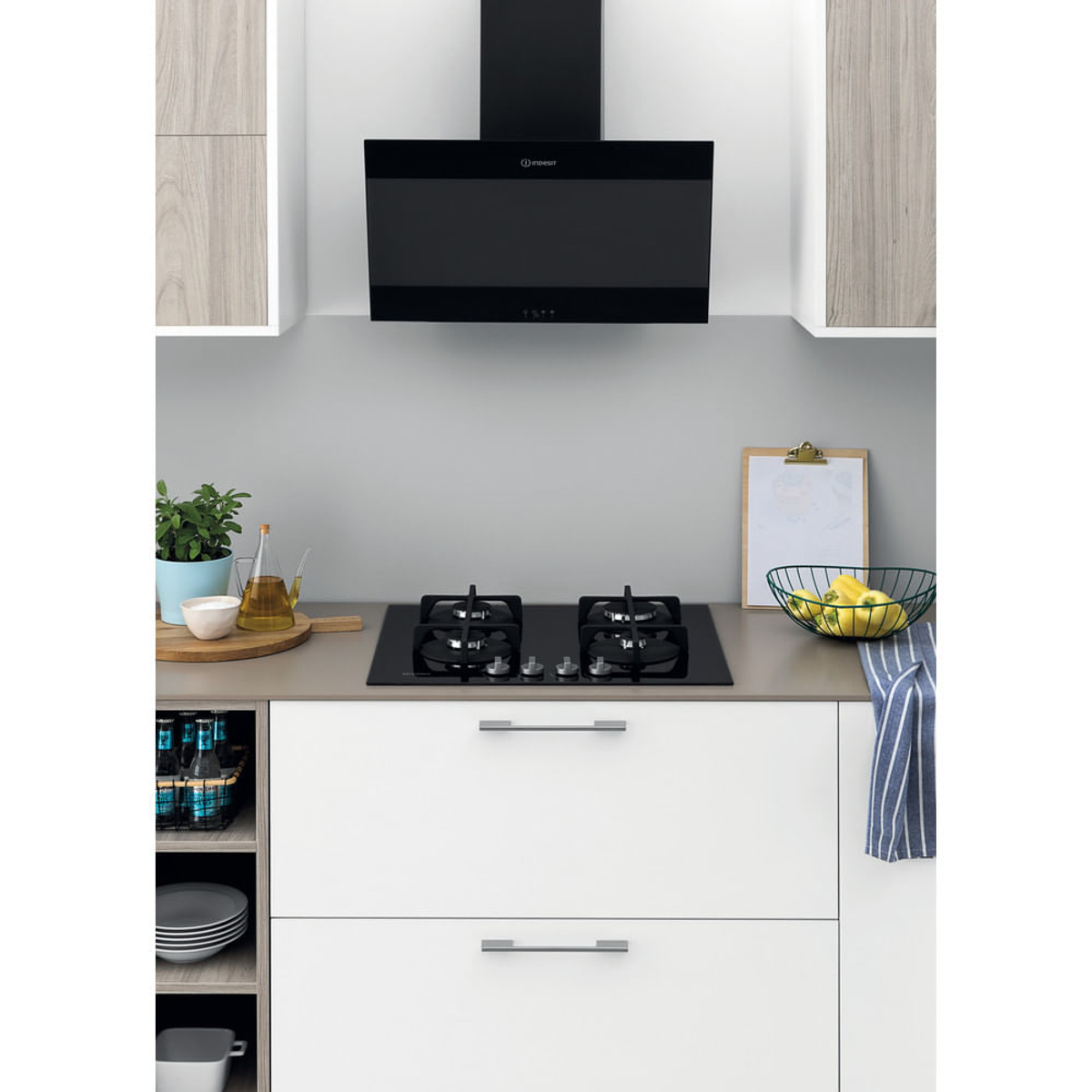 Cucina moderna con cappa nera sopra il fornello. Mobili e piano di lavoro bianchi.