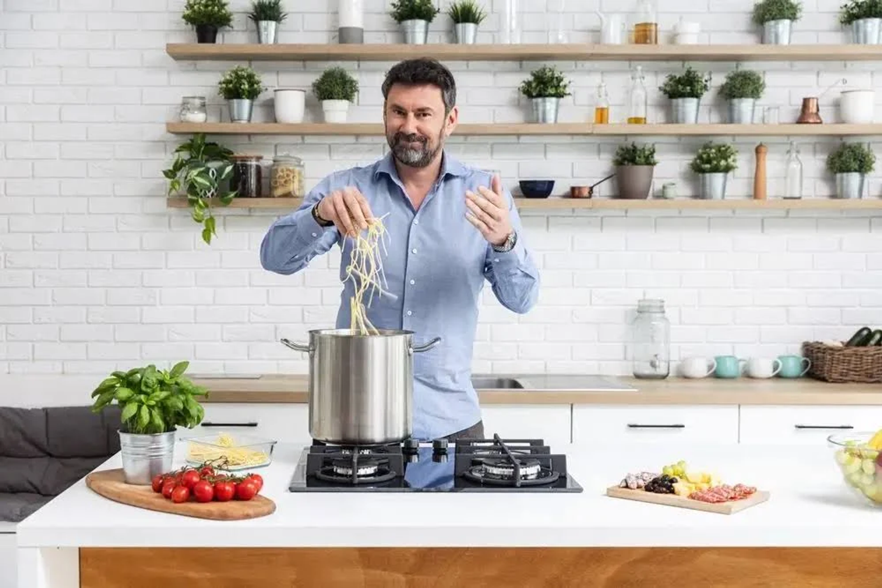 Uomo in cucina che cucina, aggiungendo pasta a una pentola sul fornello.