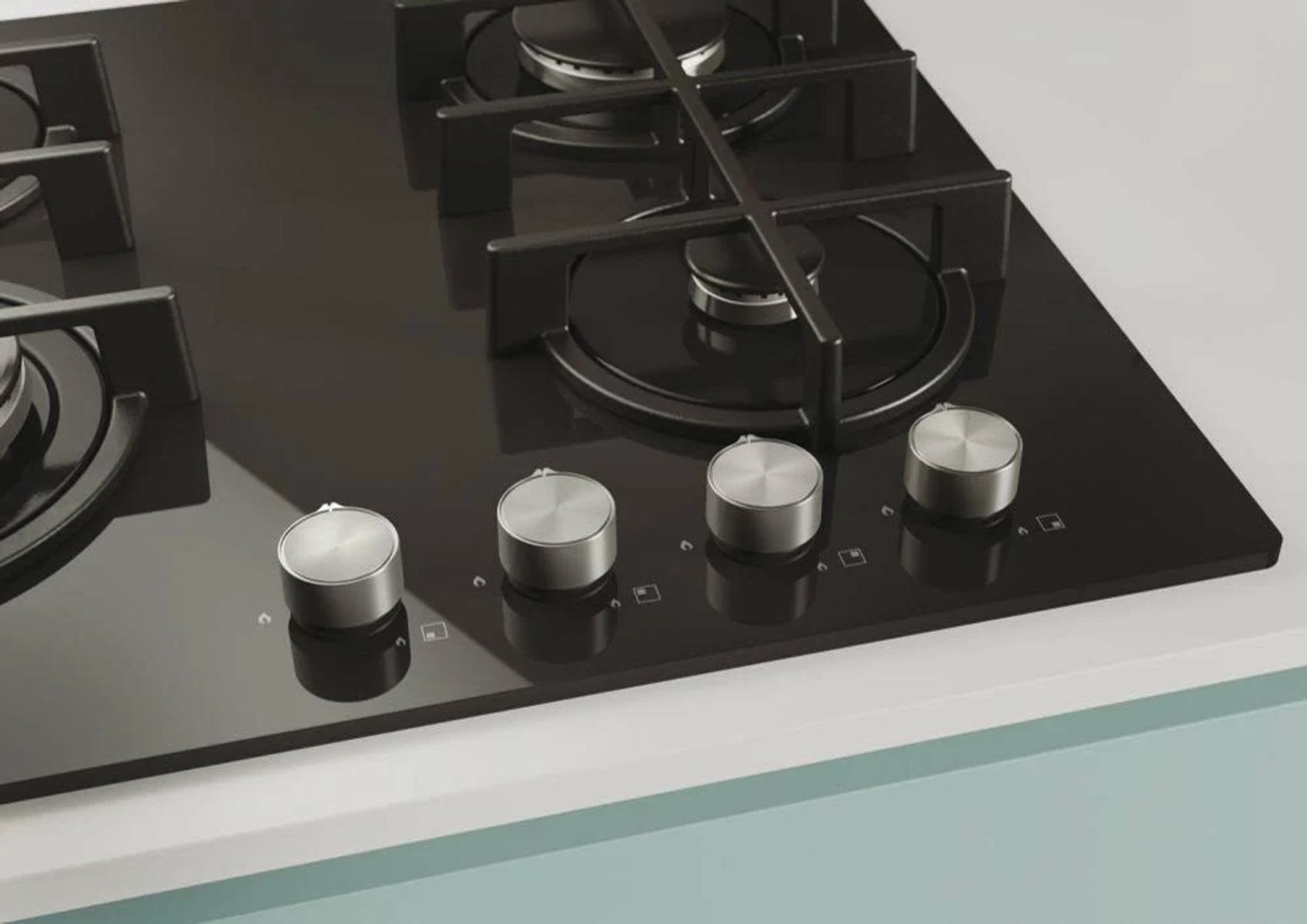 Piano cottura nero con quattro manopole argentate. Lo sfondo è azzurro.
