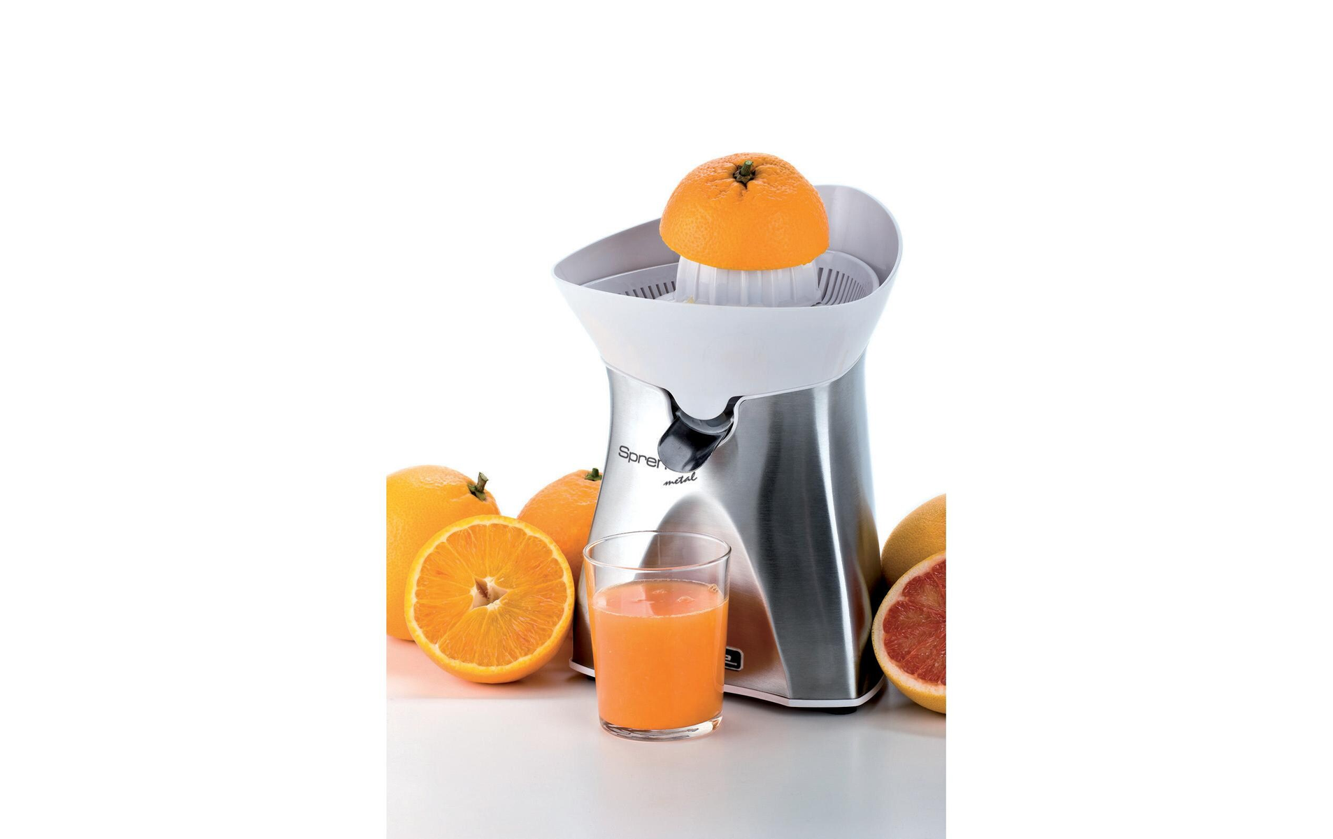 Exprimidor eléctrico con naranjas y zumo en un vaso. Media naranja visible.