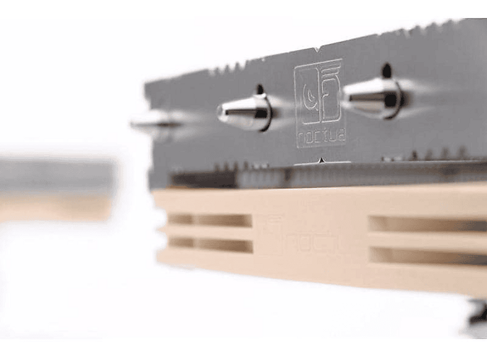 Zbliżenie komponentu komputera ze srebrnymi i beżowymi elementami, z logo Noctua.
