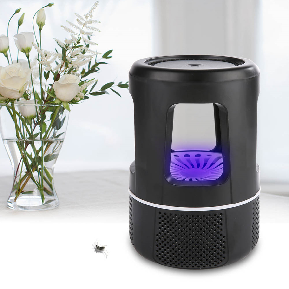 Ein schwarzer Insektenvernichter mit violettem Licht, neben einer Blumenvase und einem toten Käfer.