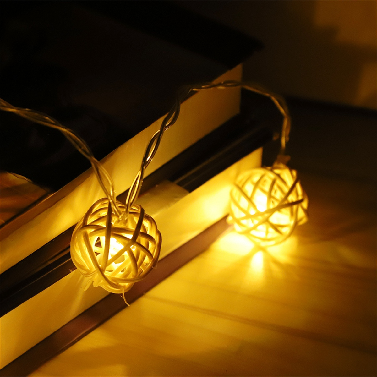 Lichterkette mit gewebten kugelförmigen Lichtern, die auf einer Holzoberfläche leuchten.