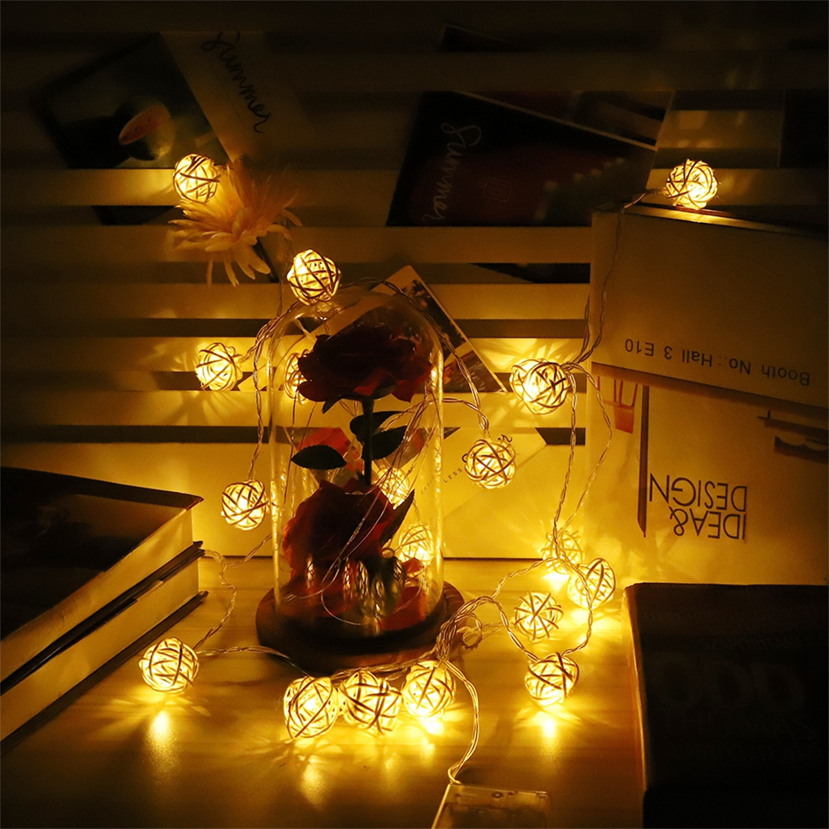 Eine Glaskuppel mit Lichterketten und einer Rose im Inneren. Der Hintergrund ist dunkel.