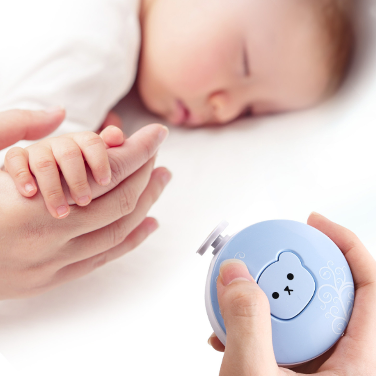 Ein schlafendes Baby, mit einer Hand, die einen Nagelknipser mit Bärenmuster hält.
