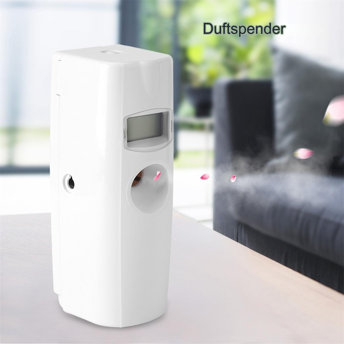 Weißer automatischer Lufterfrischer auf einem Tisch. Versprüht Duft. Im Hintergrund ein Sofa.